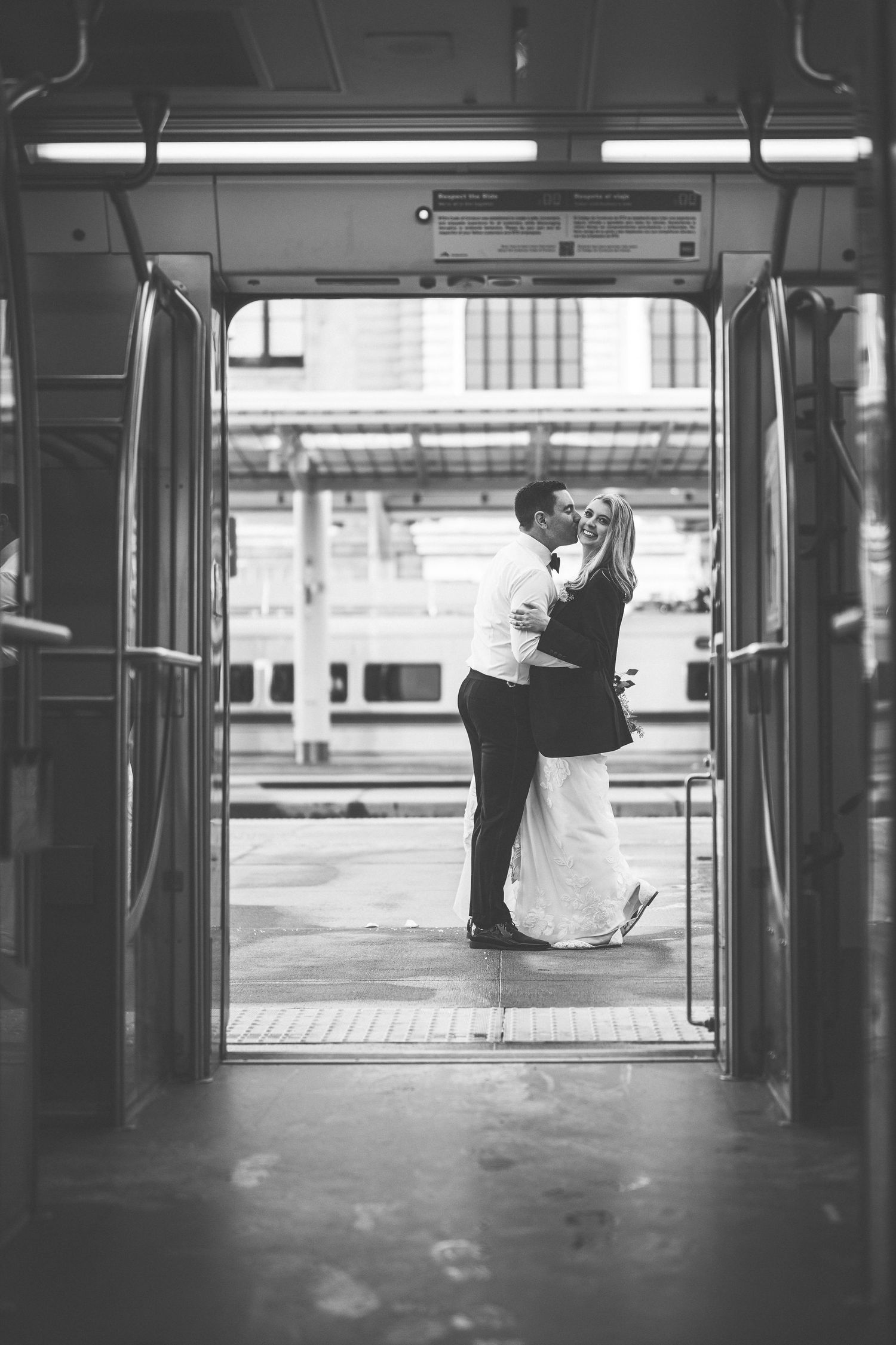 Black and white architectural shot of empty train station with distant figures.