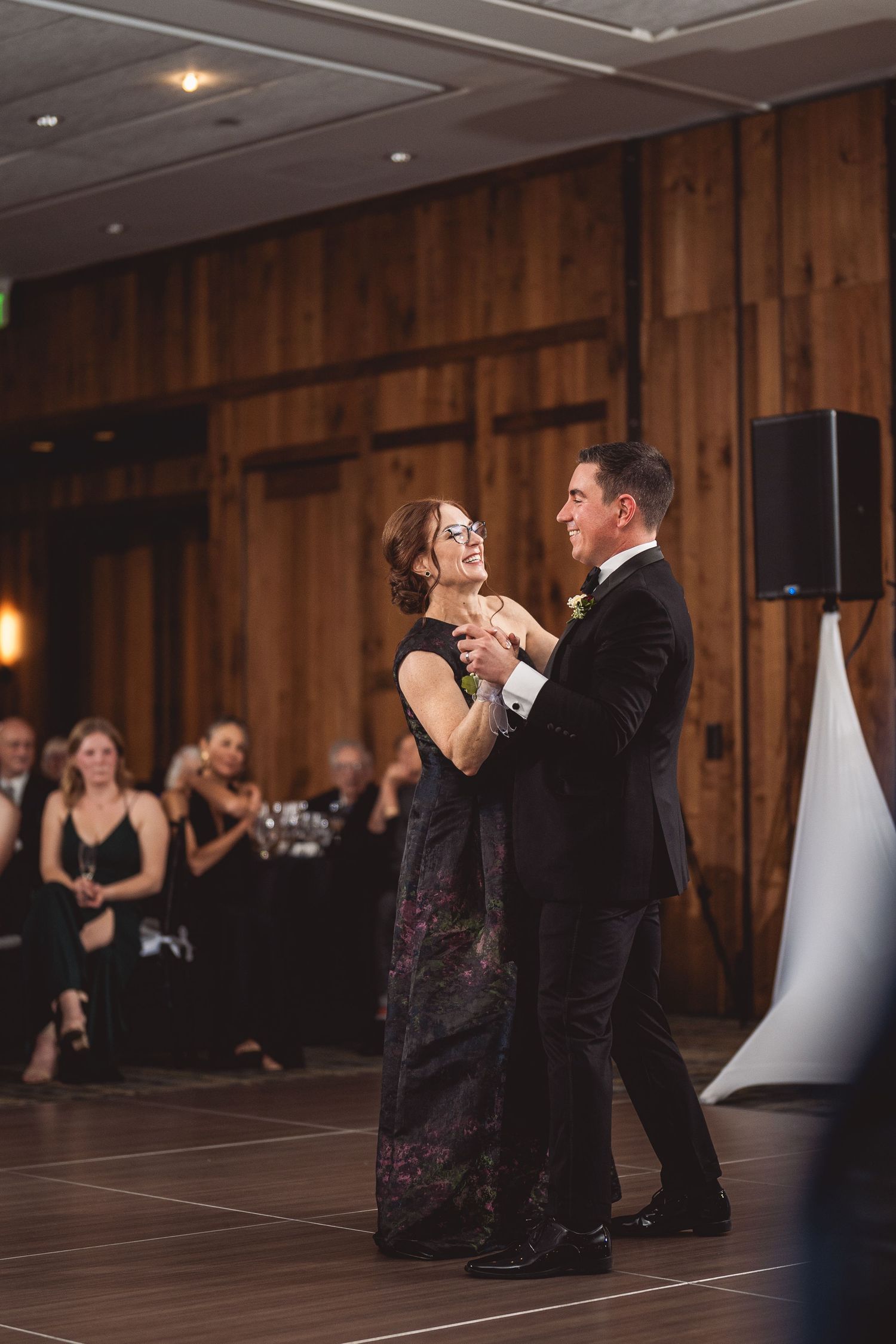 Wedding dance in a rustic ballroom with wooden walls and ambient lighting.
