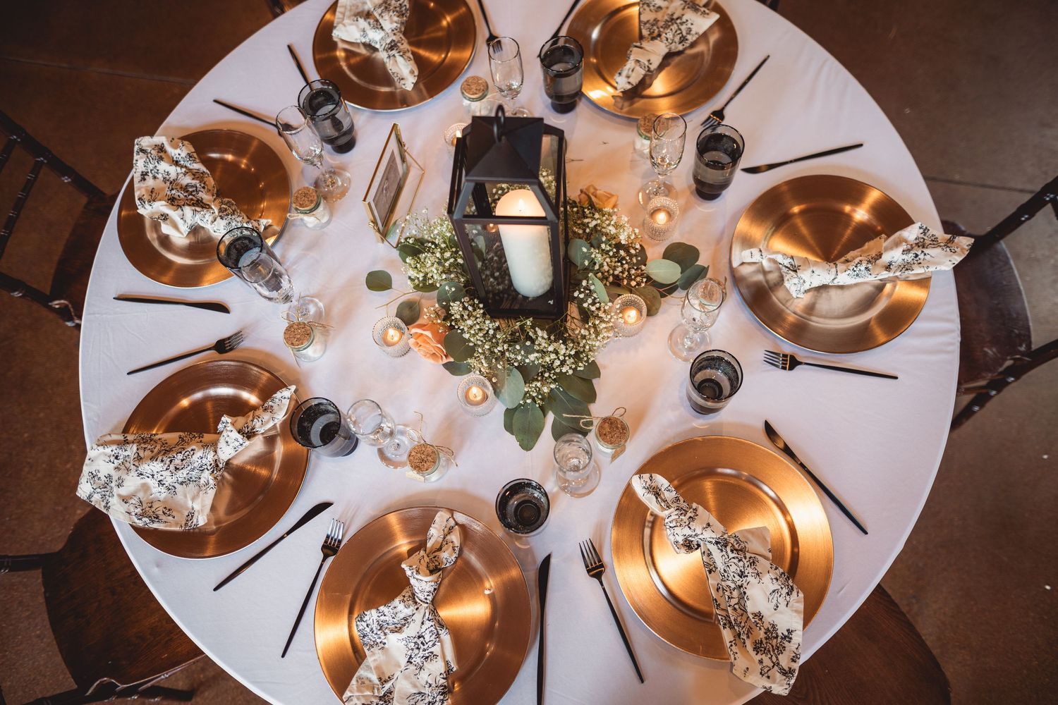 Elegant table settings with white linens and gold accents at wedding reception.
