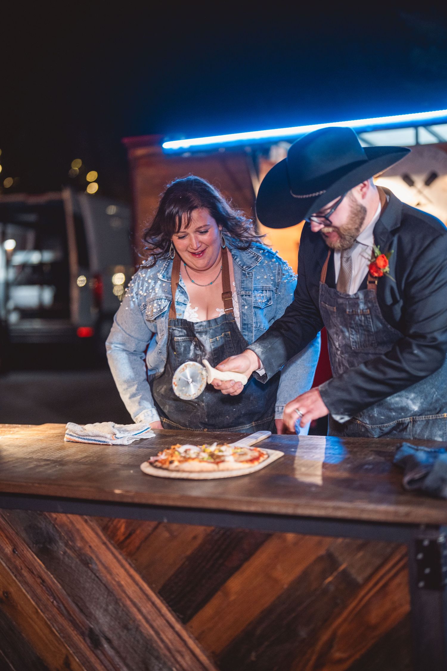 Couple enjoying refreshments at a wooden bar counter under blue ambient lighting.