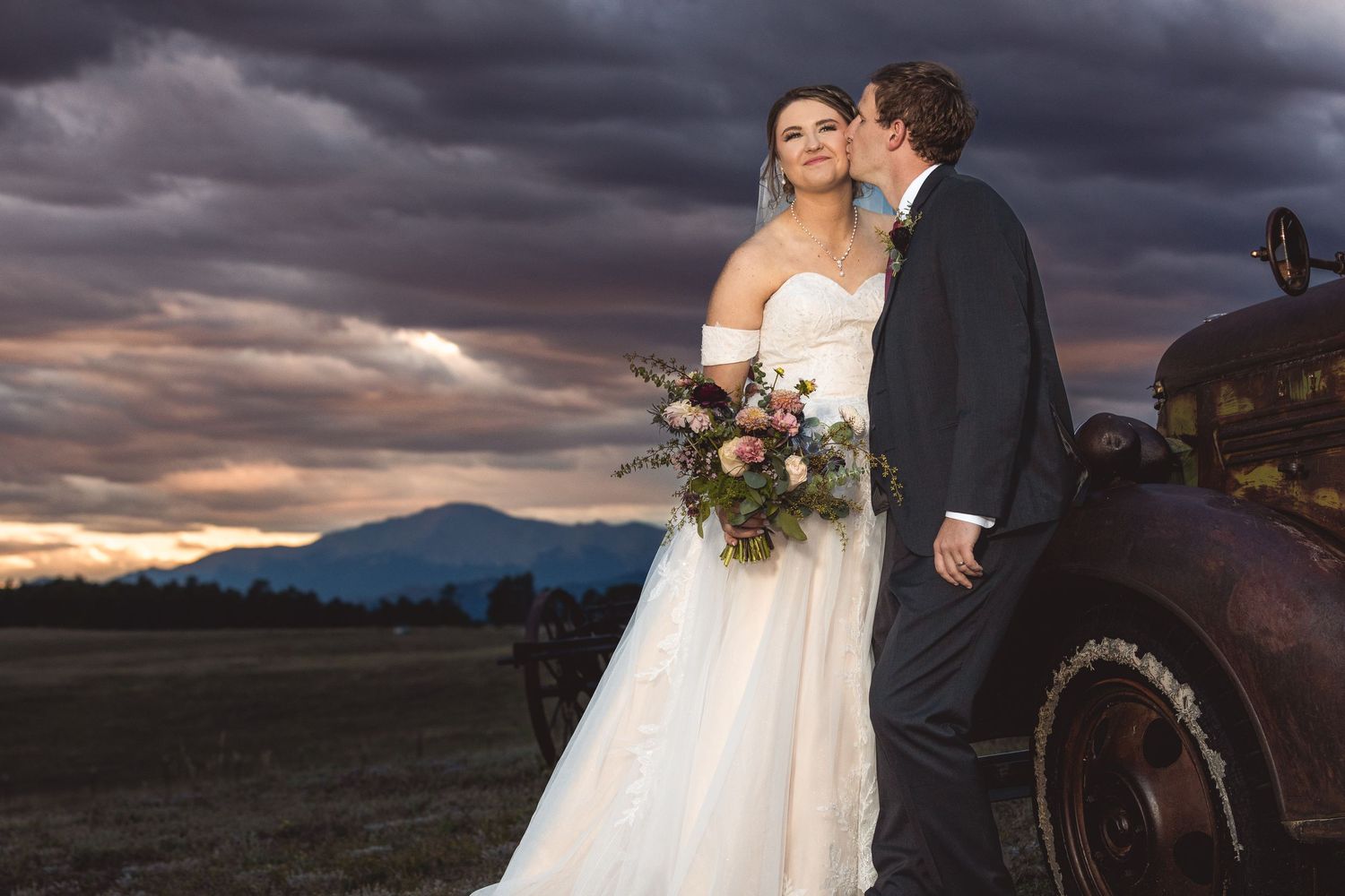 Dramatic sunset wedding portraits with mountain views and stormy skies in the background.