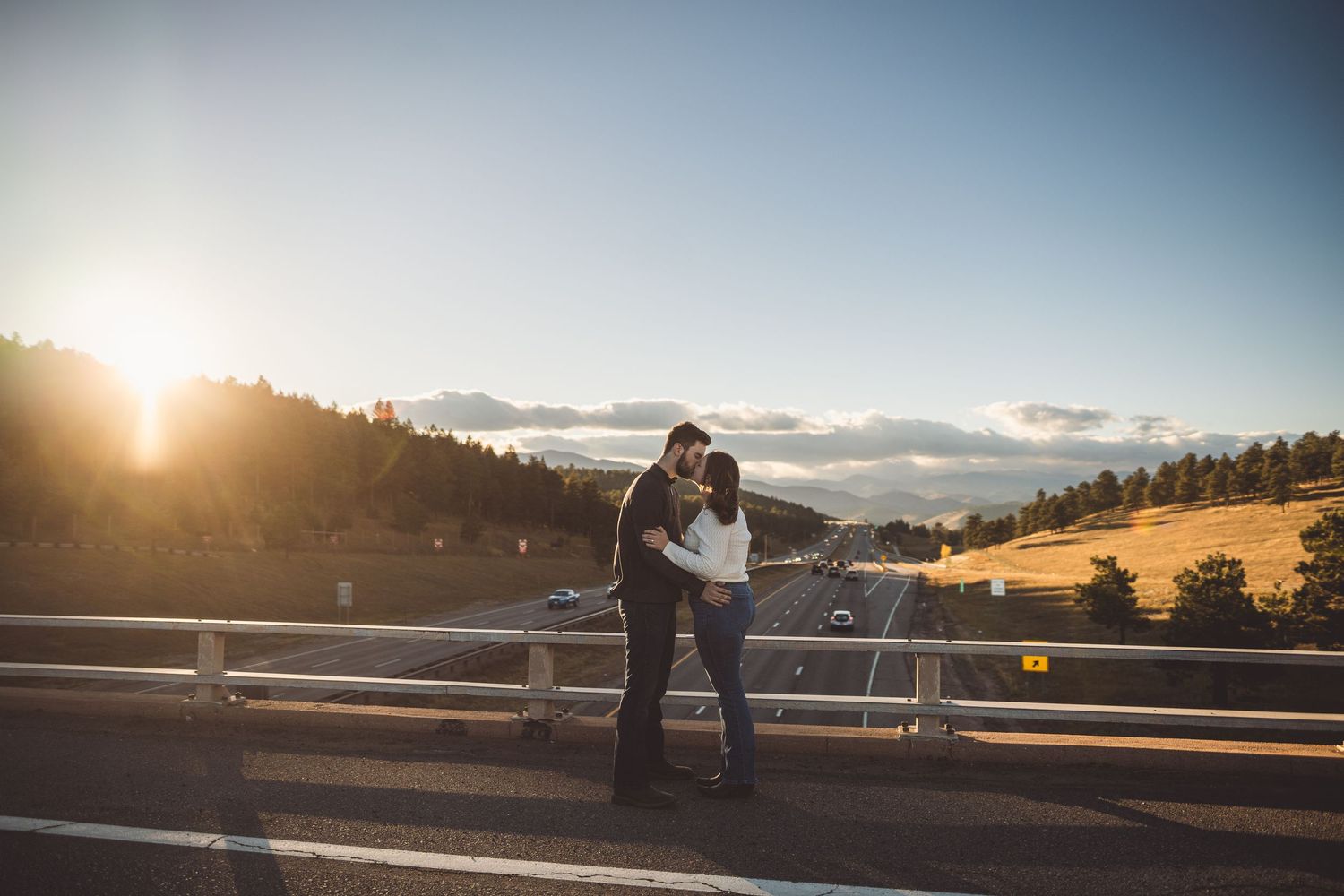 Couple sharing romantic moment at scenic mountain overlook during golden hour.