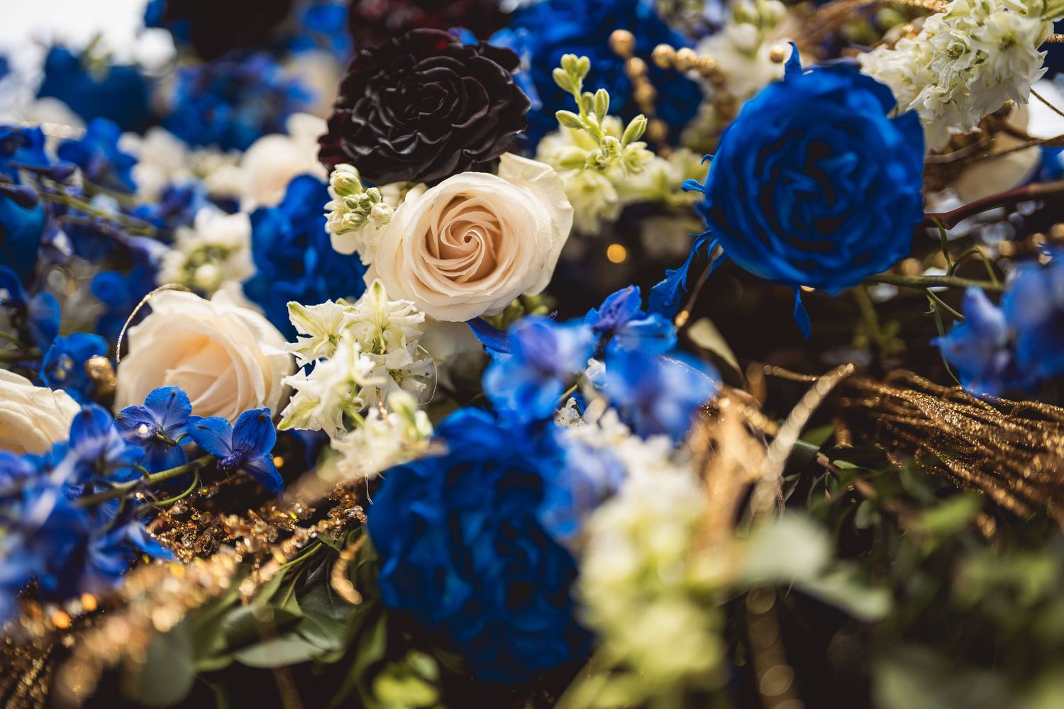 Wedding floral arrangements featuring vibrant blue roses and cream colored flowers.