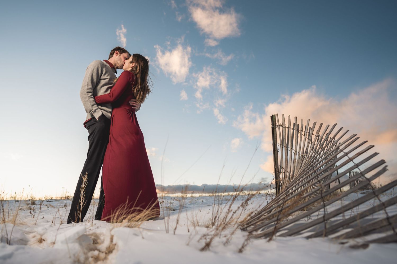 Beach engagement photos with weathered wooden fences during golden hour.