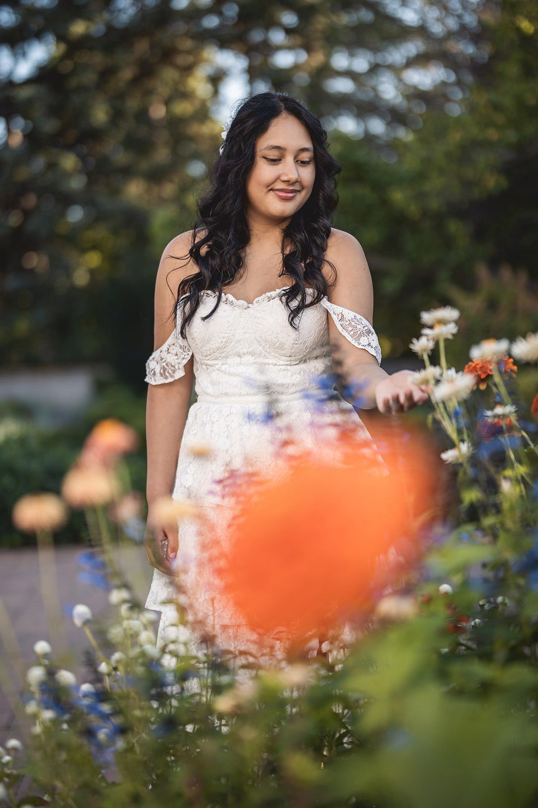 Dreamy garden portrait with colorful flowers and soft bokeh effects in natural lighting.