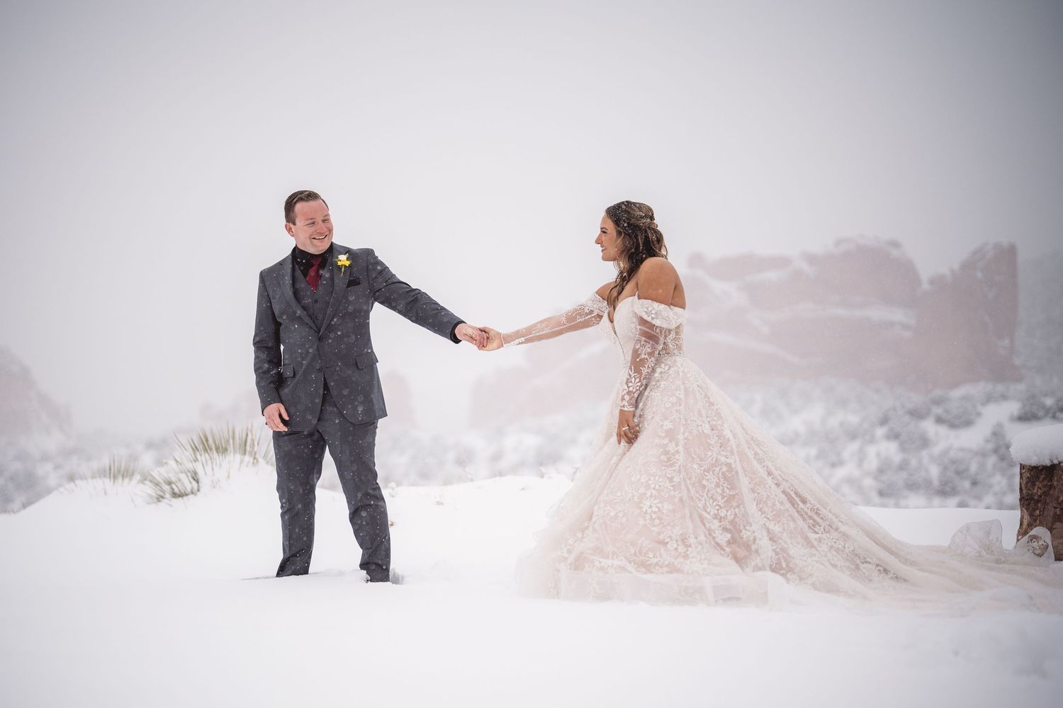 Couple dancing and twirling in fresh snow during their winter mountain wedding shoot.