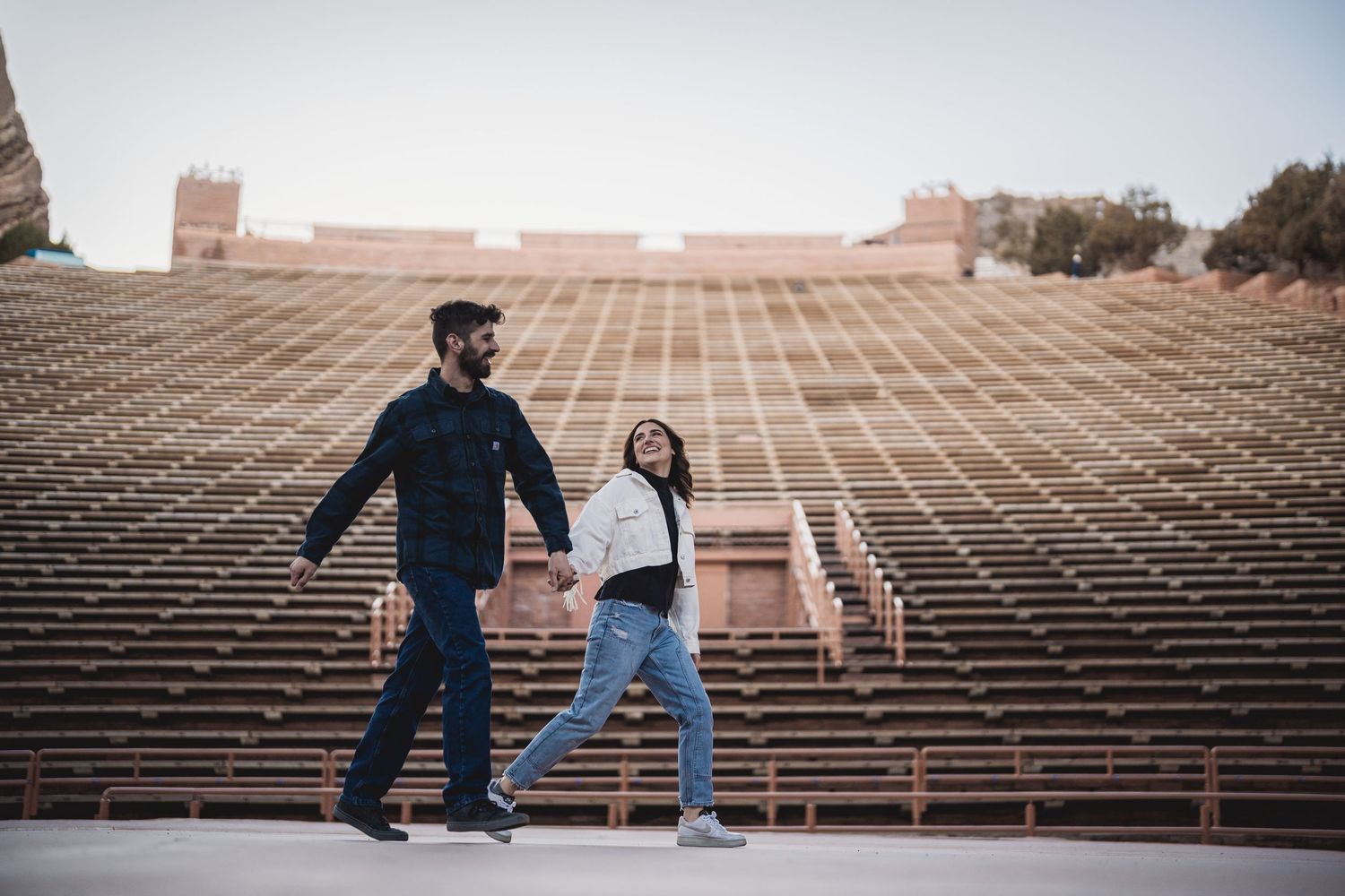A couple poses playfully on stadium bleachers during a lifestyle photoshoot.