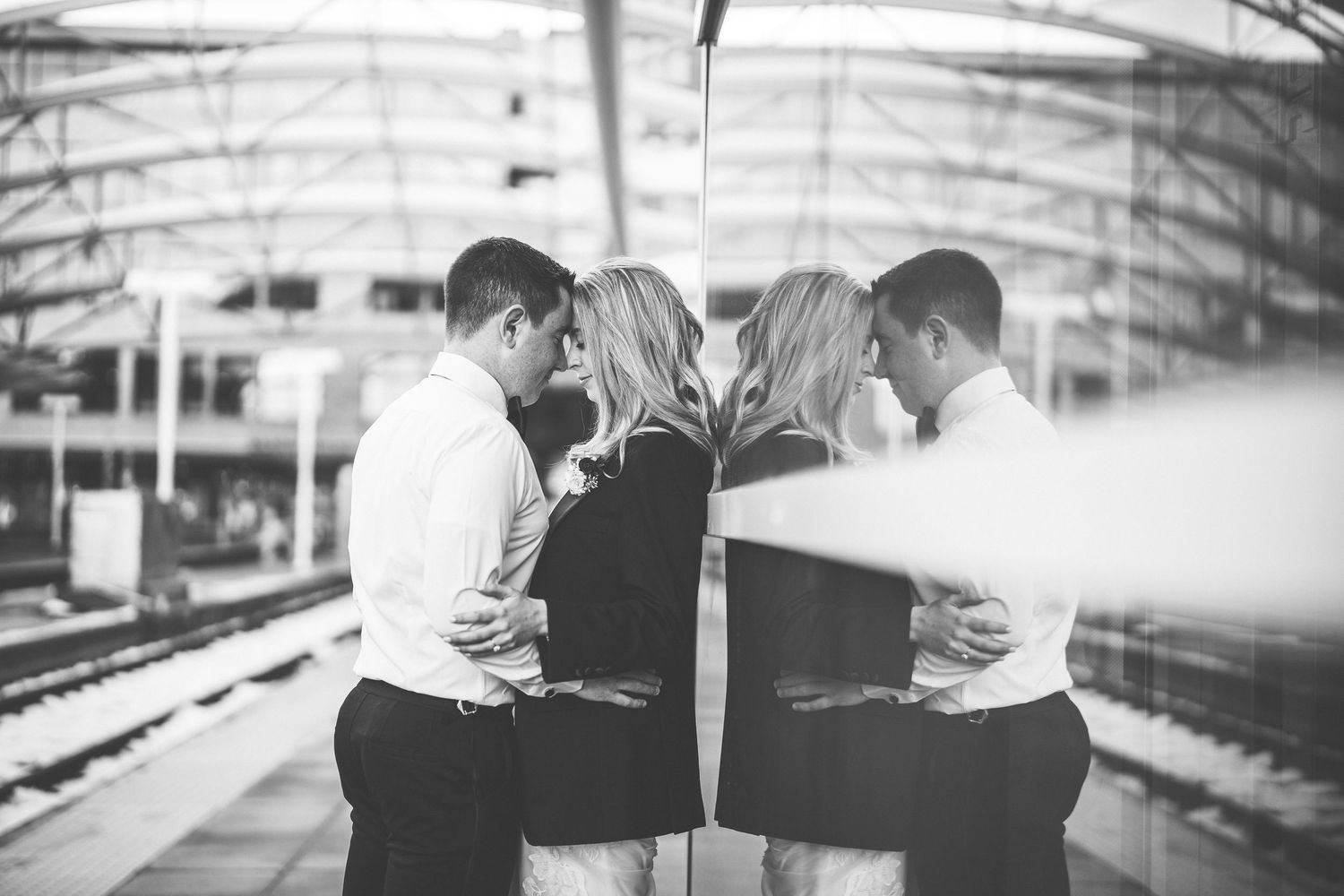 Black and white wedding photos on industrial train platform with dramatic composition.