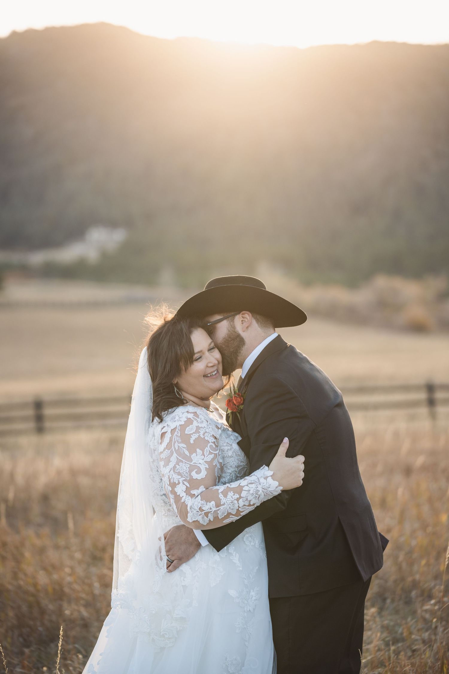 Romantic sunset moment captured during western-themed wedding in open field.