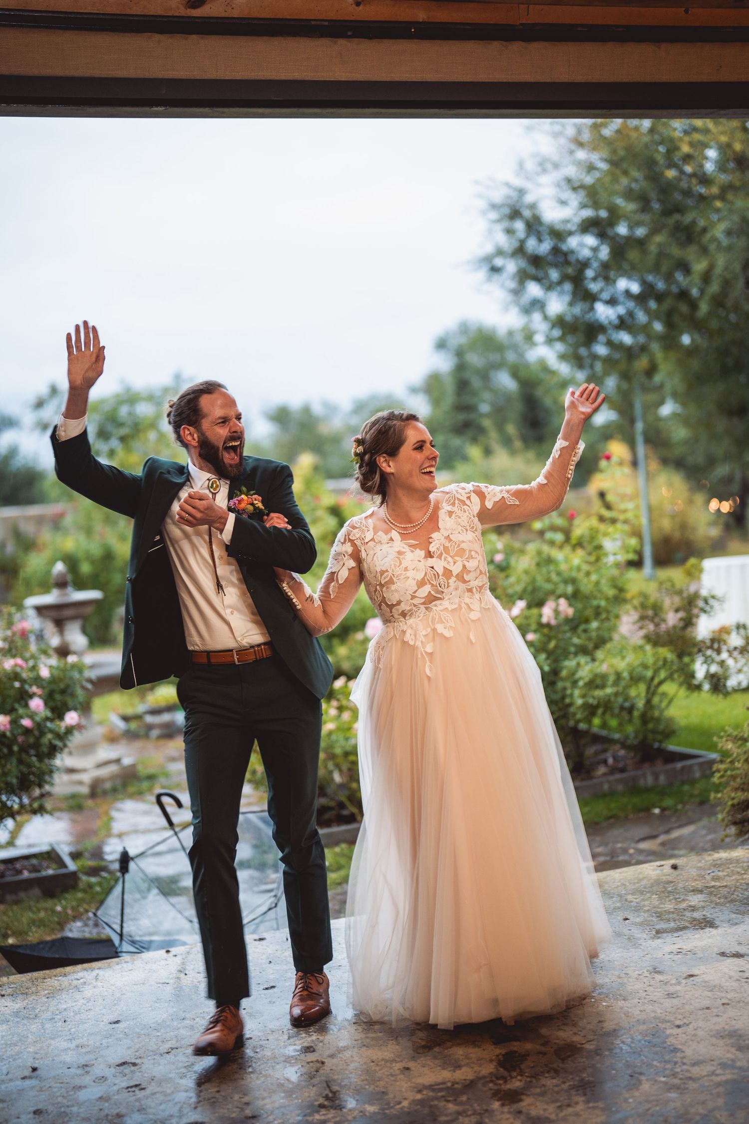Couple celebrating with raised arms in joyful dance on their wedding day.