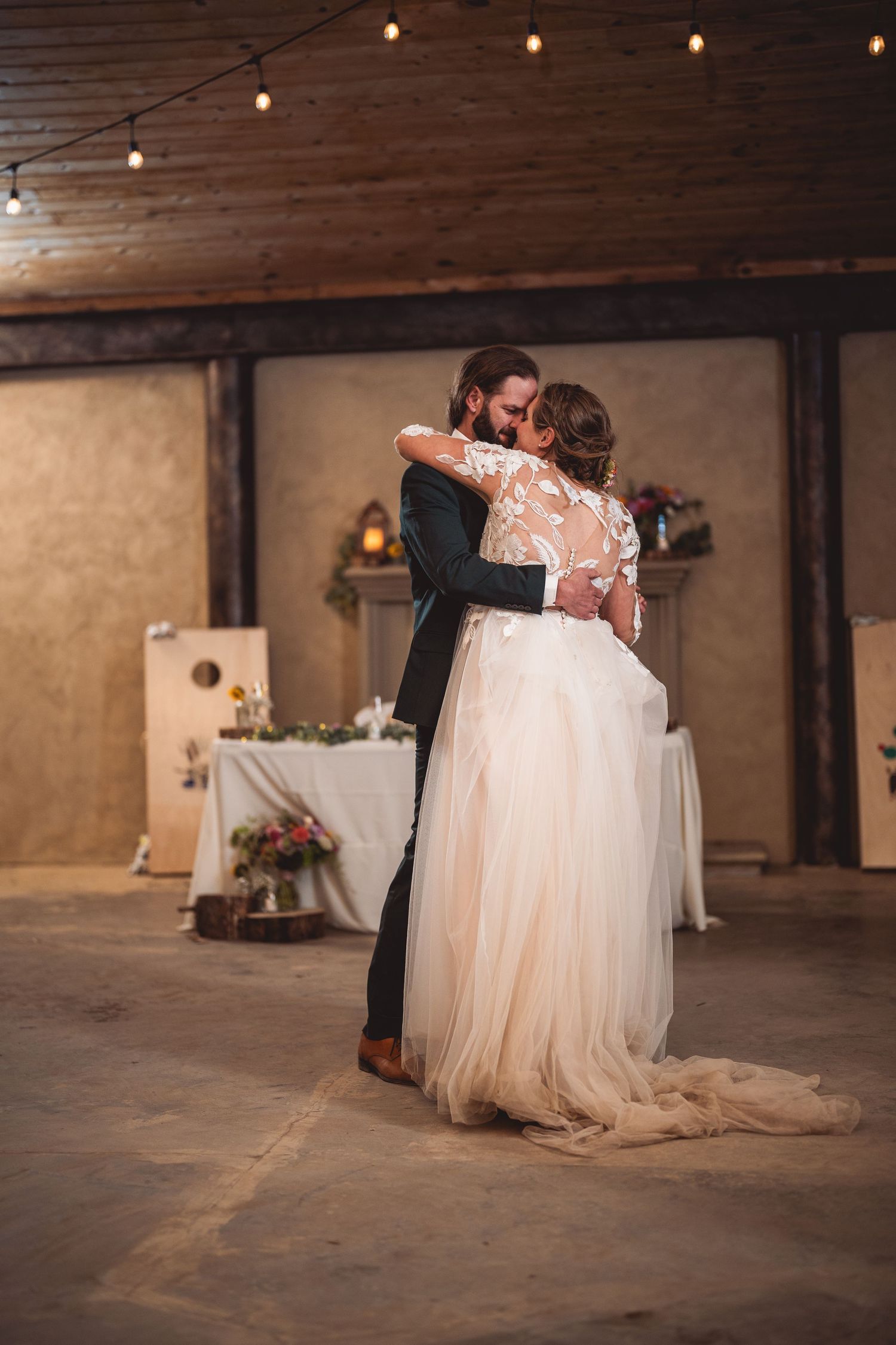 Wedding couple dances in an industrial-style venue with concrete floors and romantic lighting.