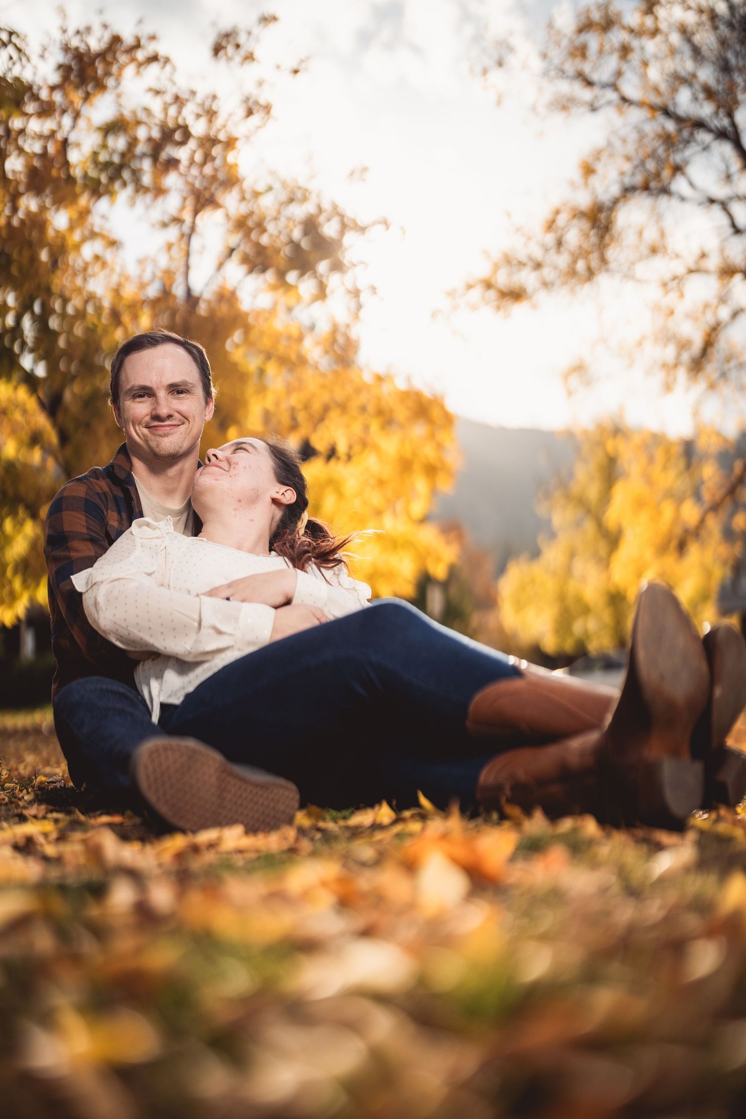 Couple lying in autumn leaves during a fall engagement session.