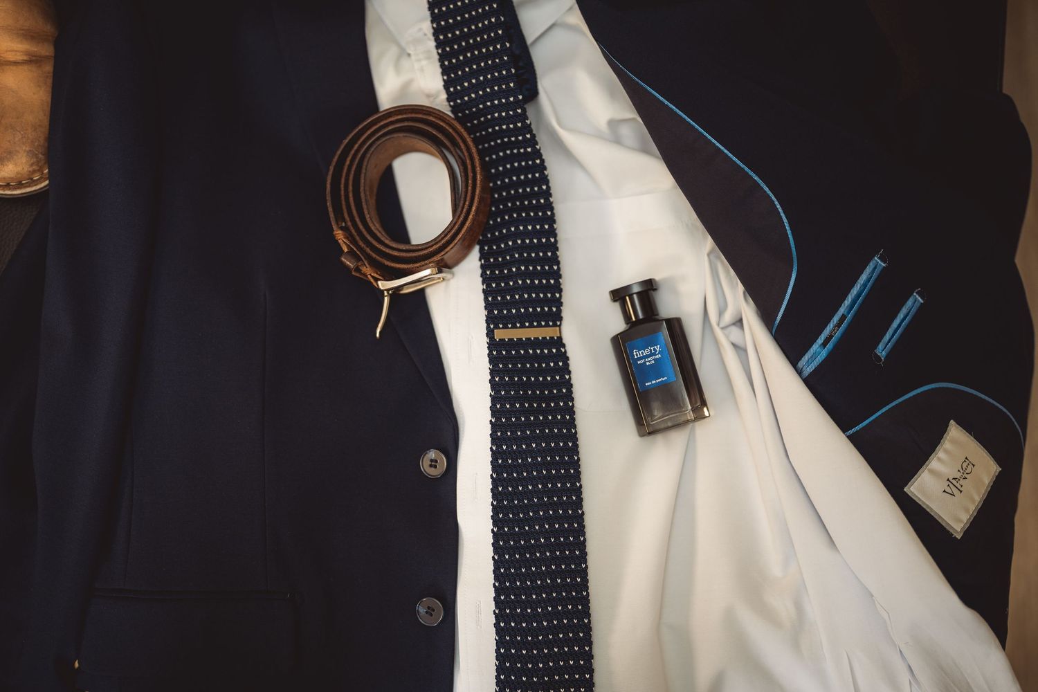 Close-up details of a navy suit with polka dot tie and white dress shirt.