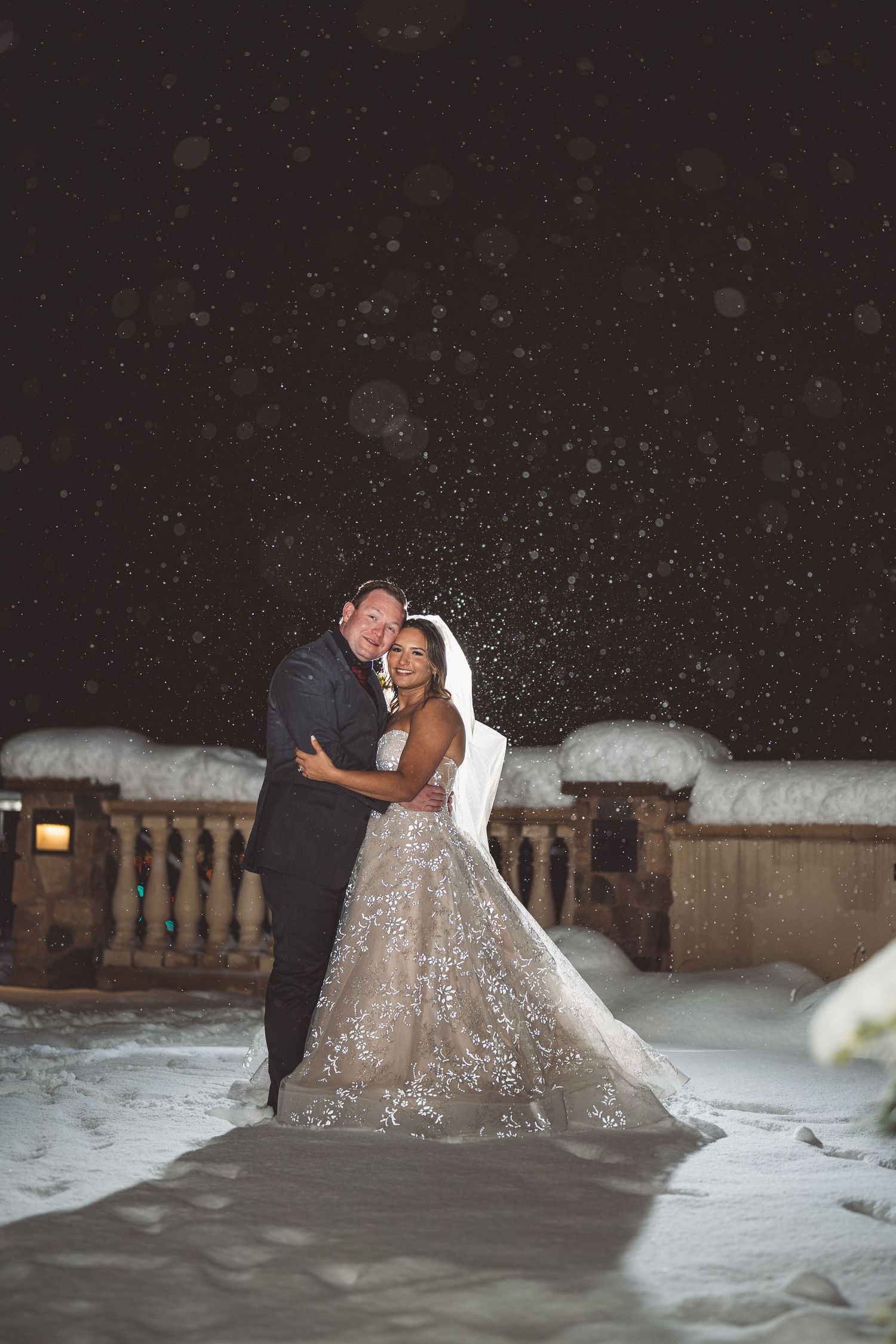 A romantic wedding moment captured in a snowy evening setting with ambient lighting.