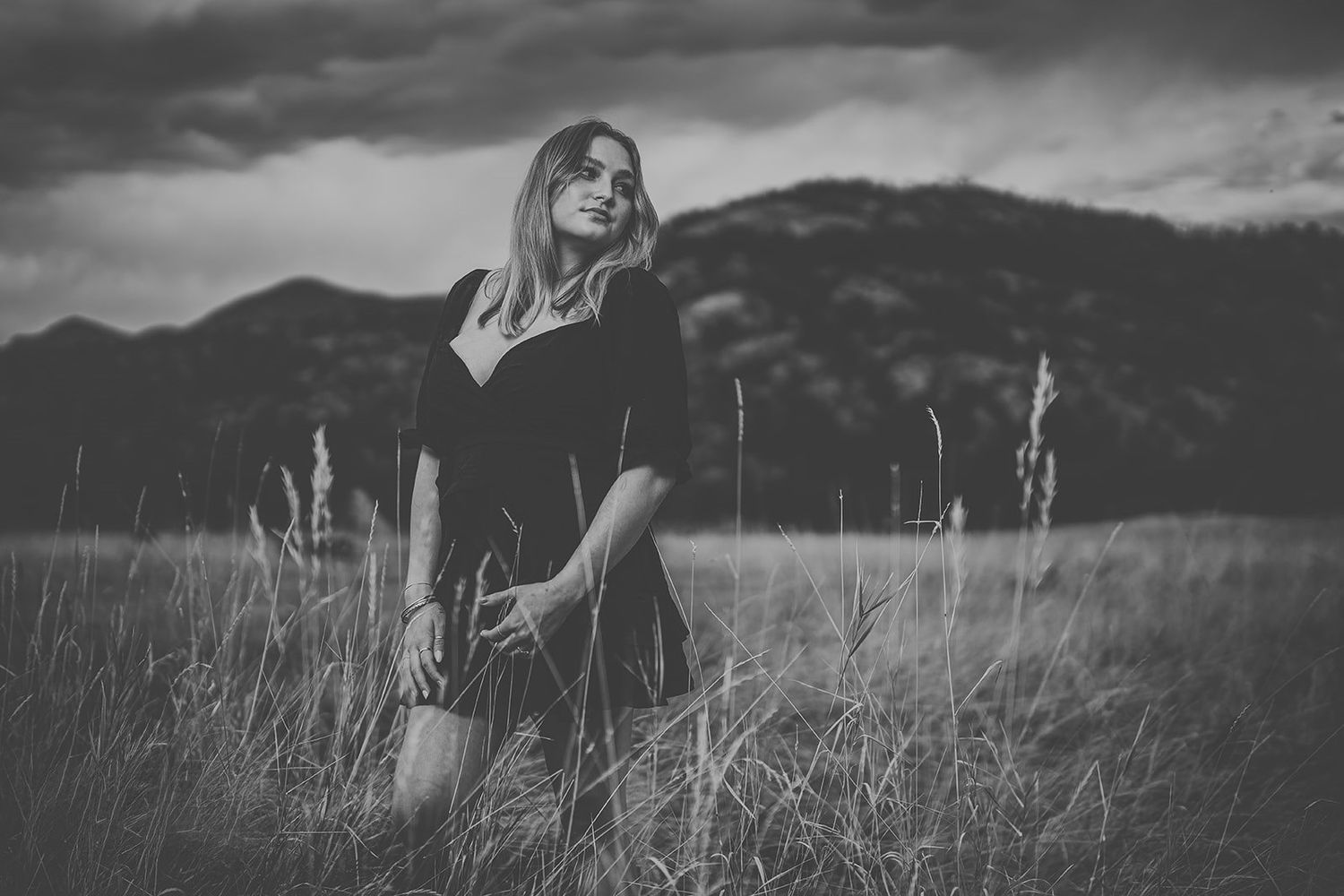 Black and white landscape photo of mountains with dramatic stormy skies overhead.