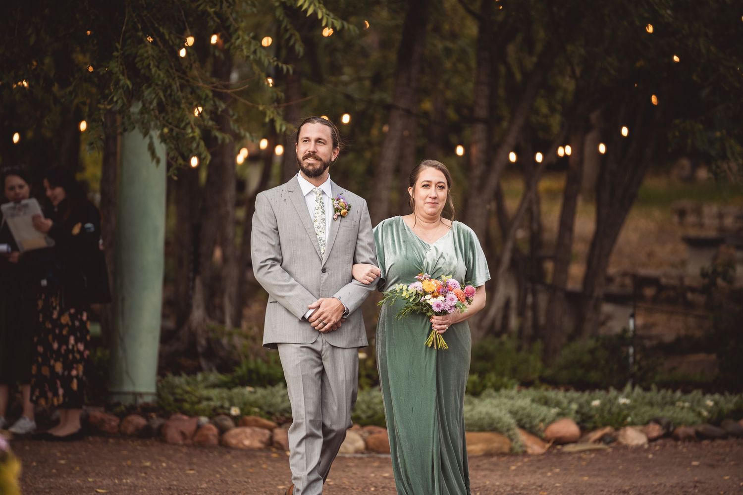 Outdoor wedding ceremony setup with string lights and rustic decor at dusk.