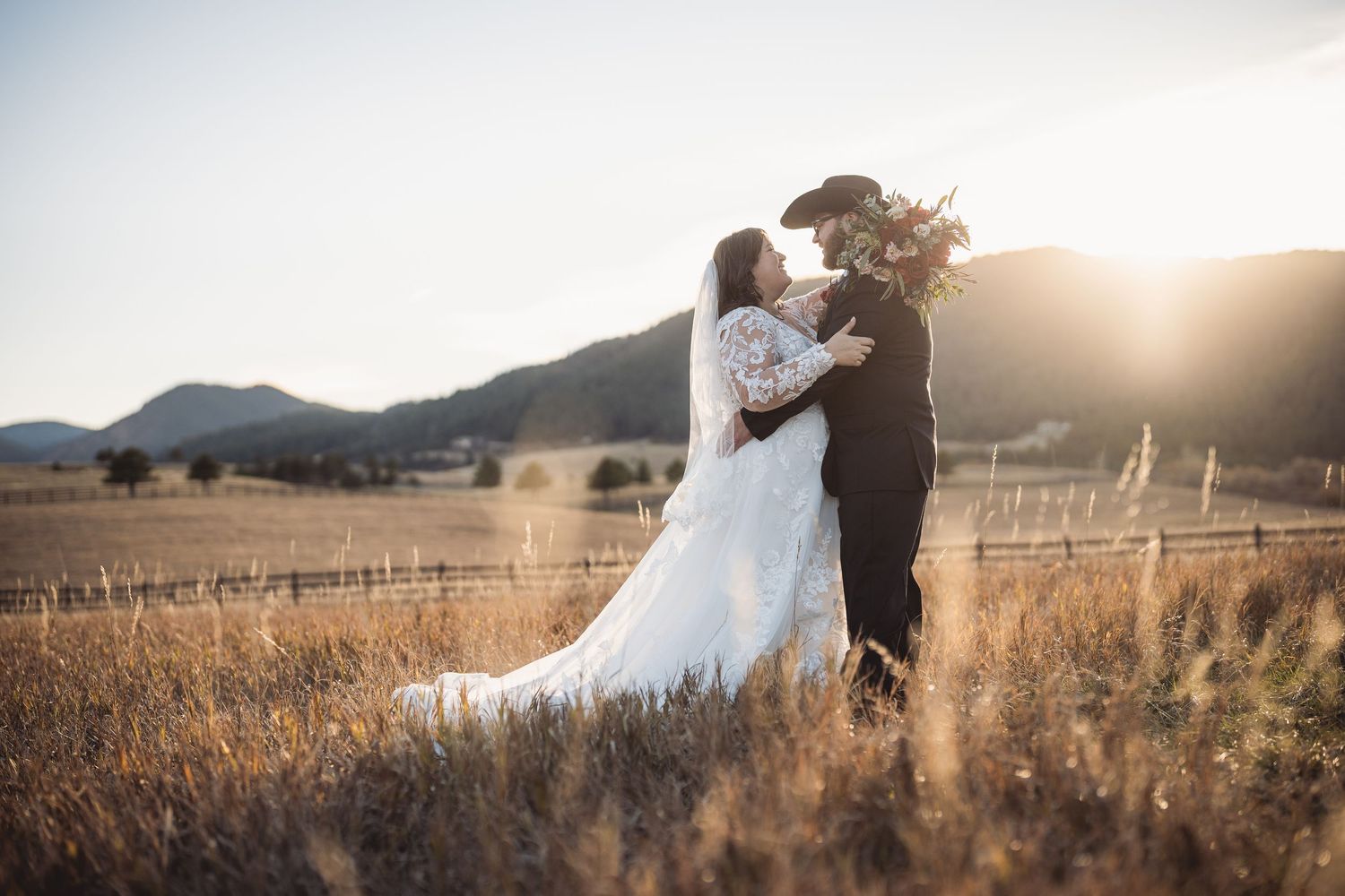 Romantic wedding portraits at sunset with mountain landscape in background.