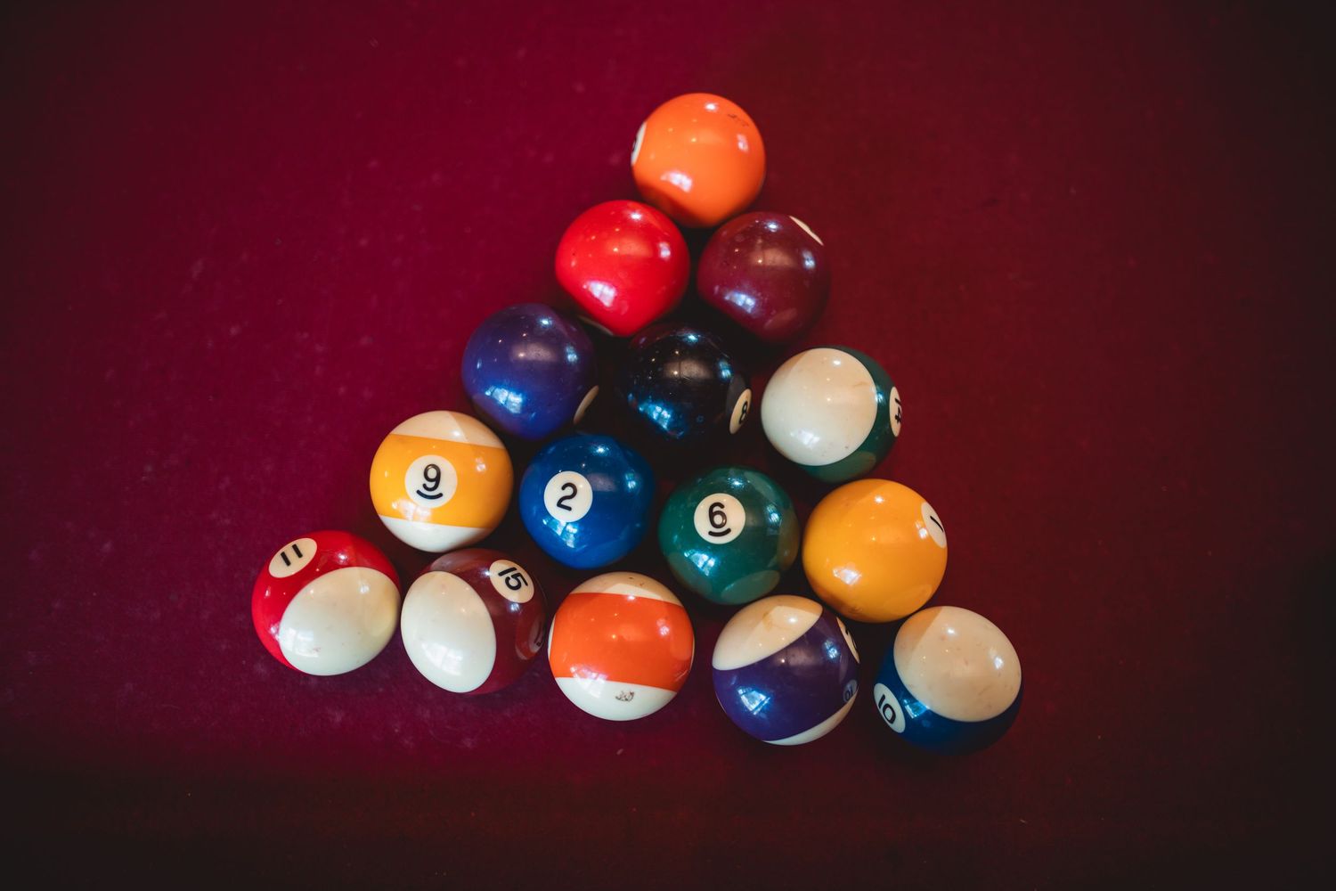 Colorful billiard balls arranged artistically on a red velvet surface.
