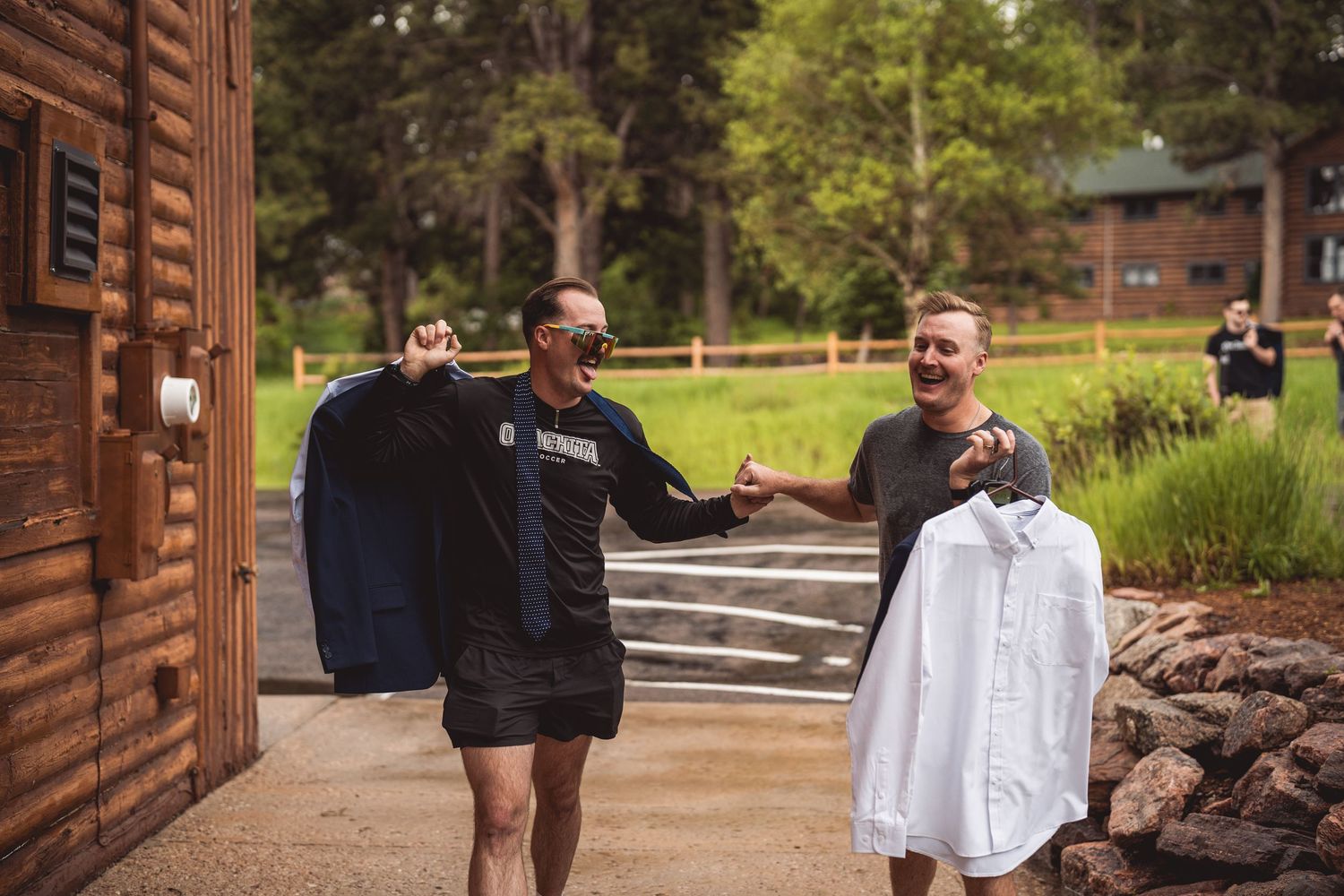 Group gathering outside rustic wooden lodge surrounded by pine trees.