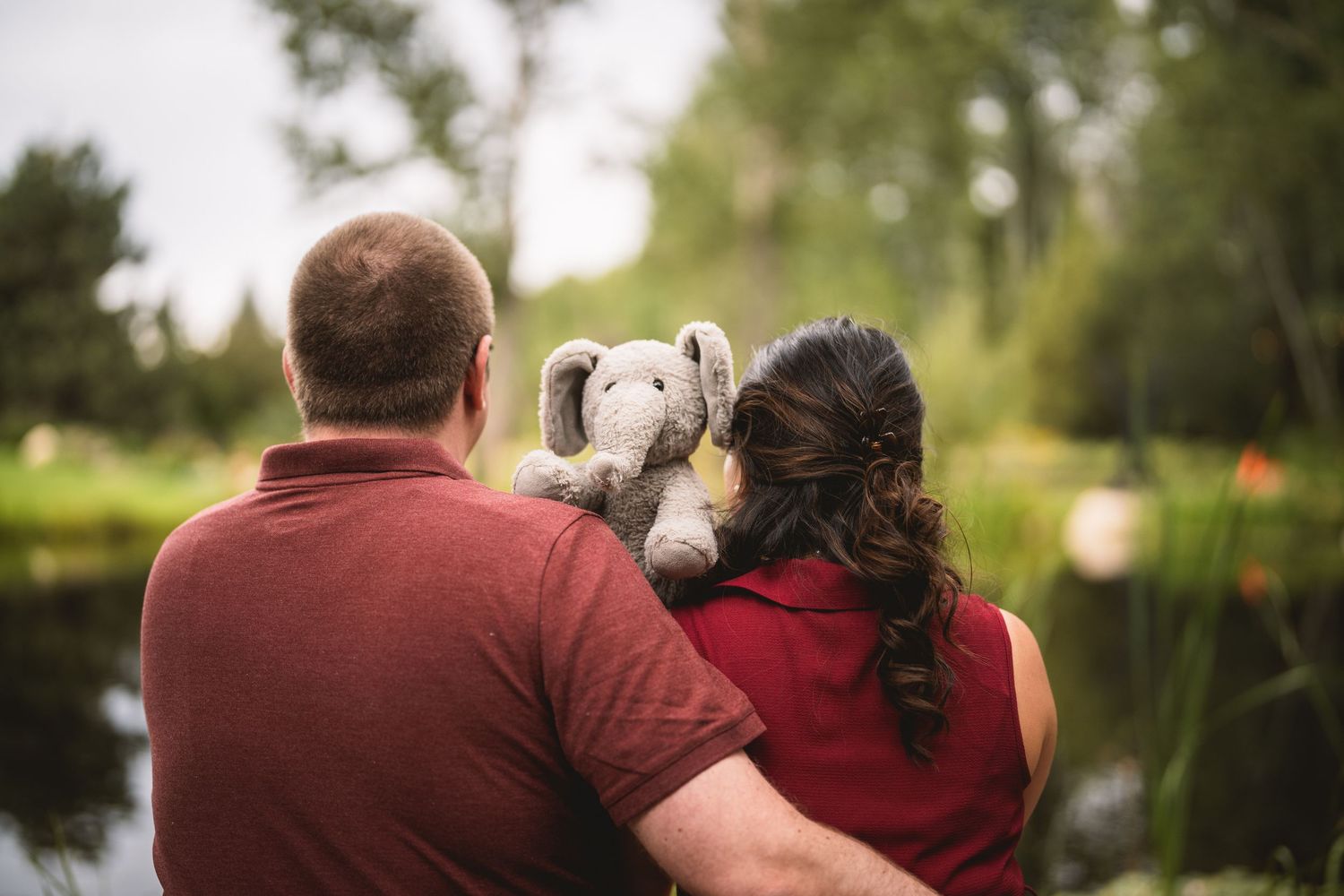 A couple relaxes together on an outdoor bench in a peaceful garden setting.