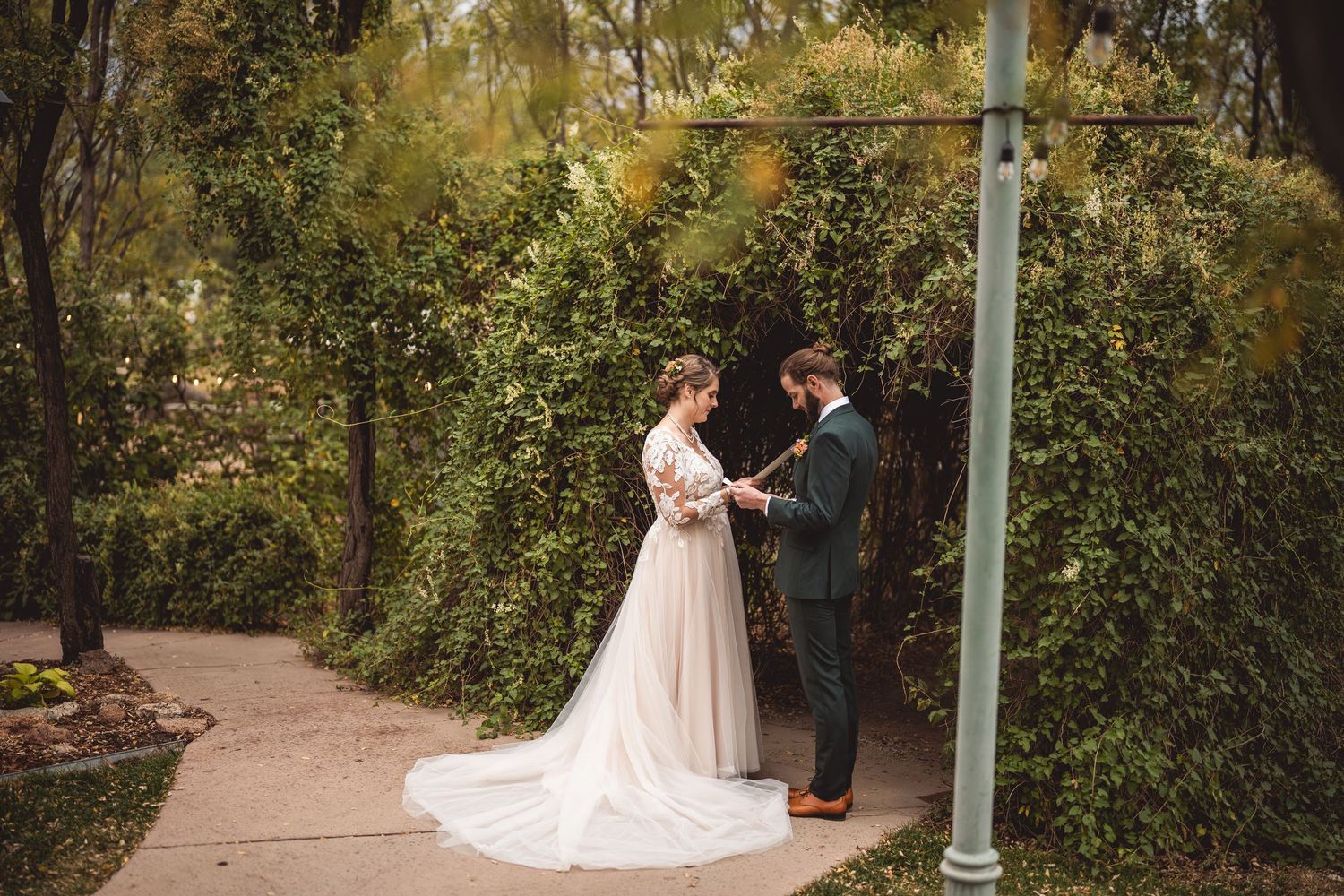 Garden pathway wedding scene with couple surrounded by lush green trees.