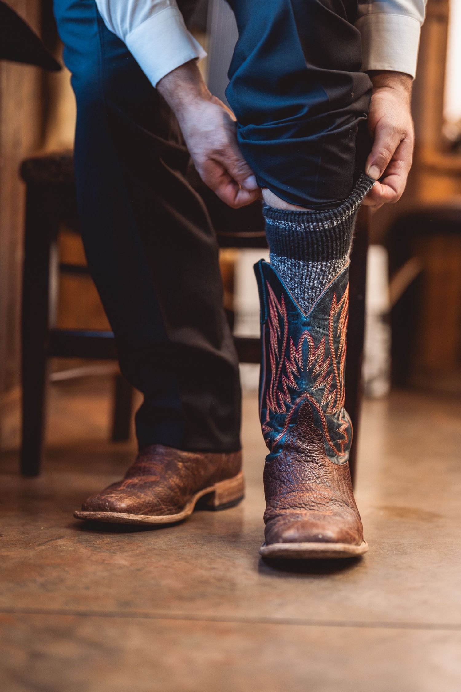 Detail shot of cowboy boots with colorful sock patterns at a wedding.