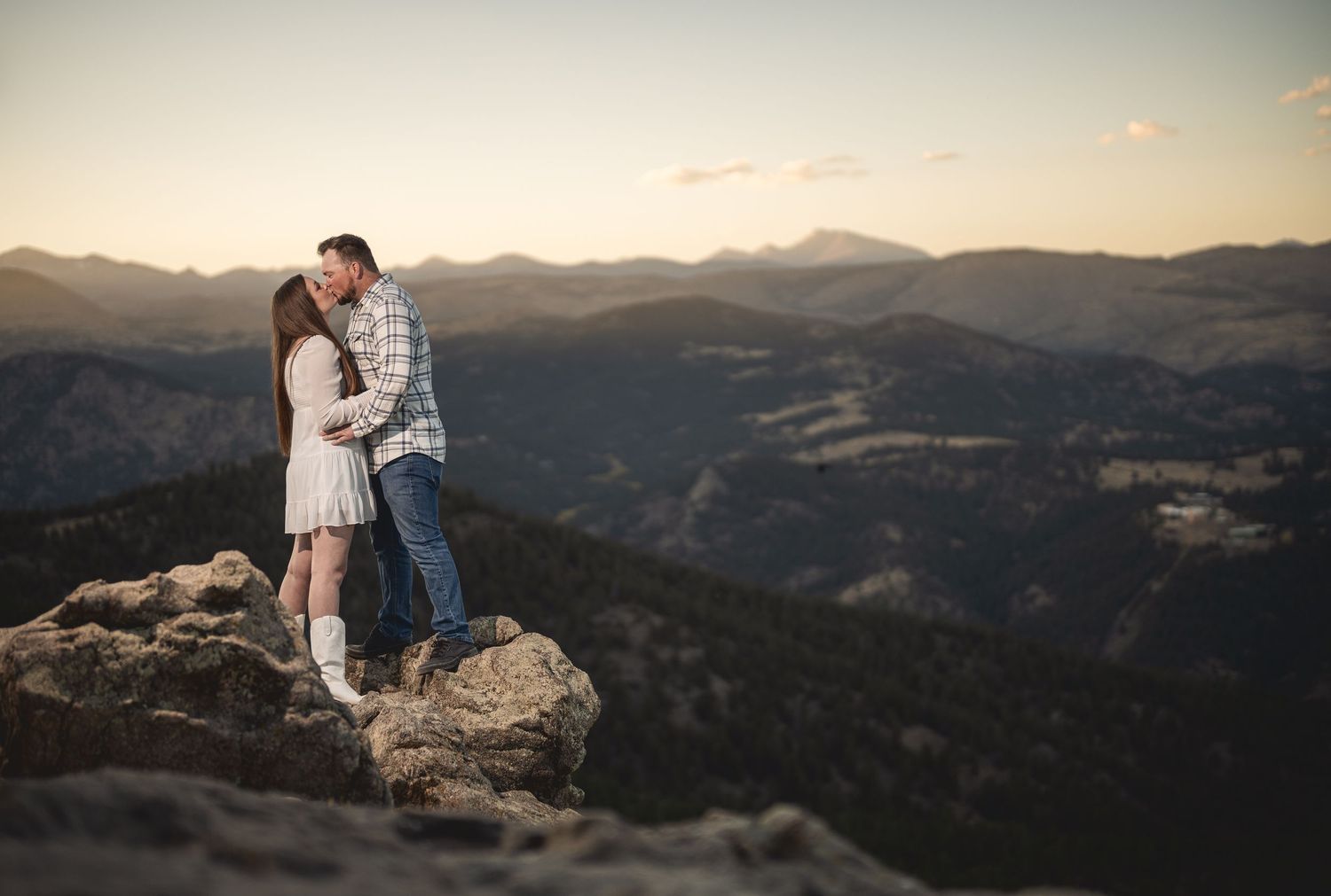Romantic sunset engagement photos on a mountain overlook with panoramic valley views.