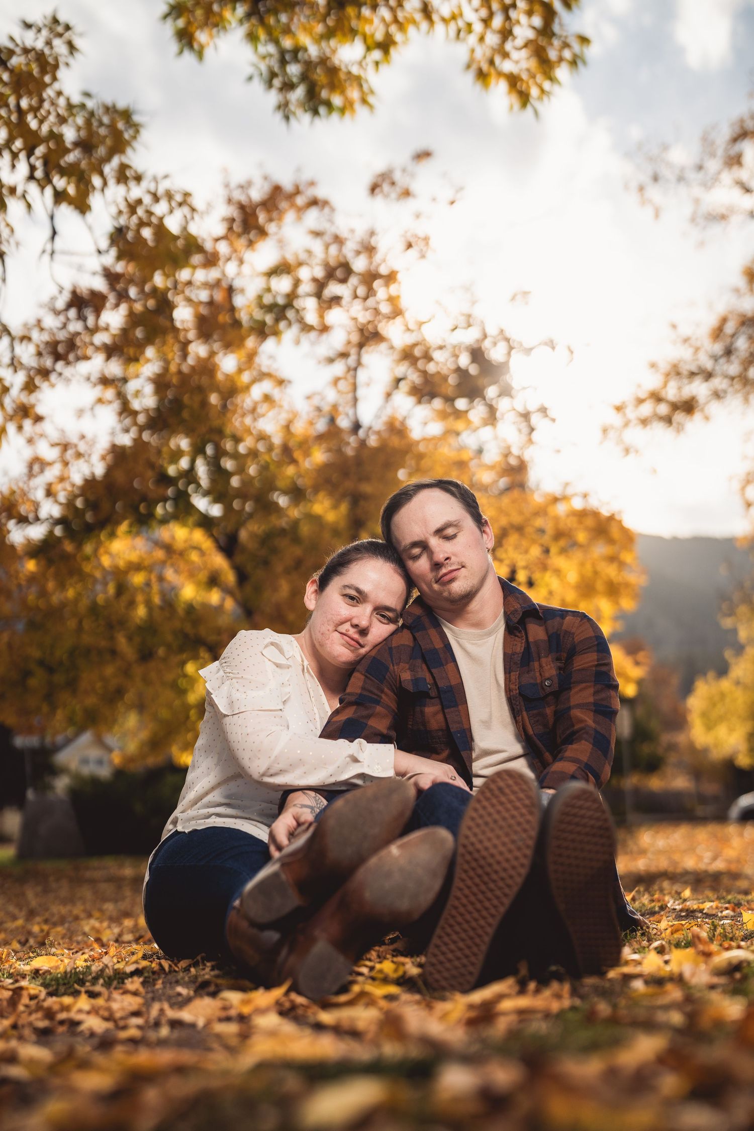 Couple relaxing on carpet of fall leaves during autumn photoshoot.