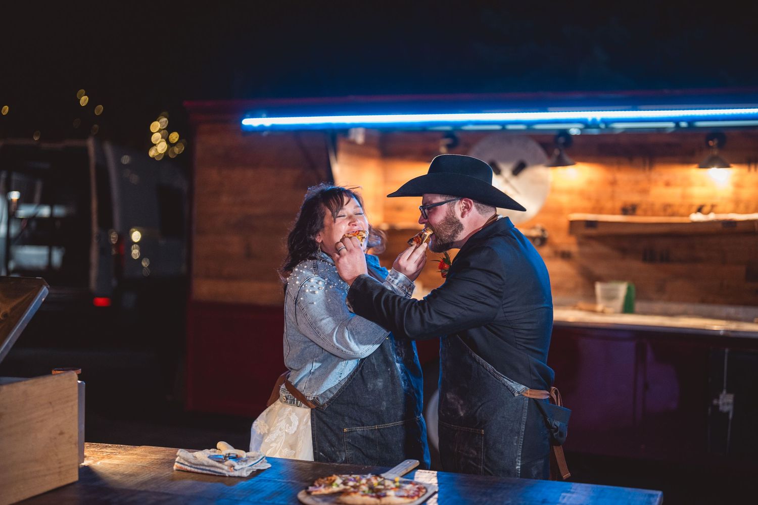 Wedding reception scene with blue neon lighting and rustic wooden bar decor.