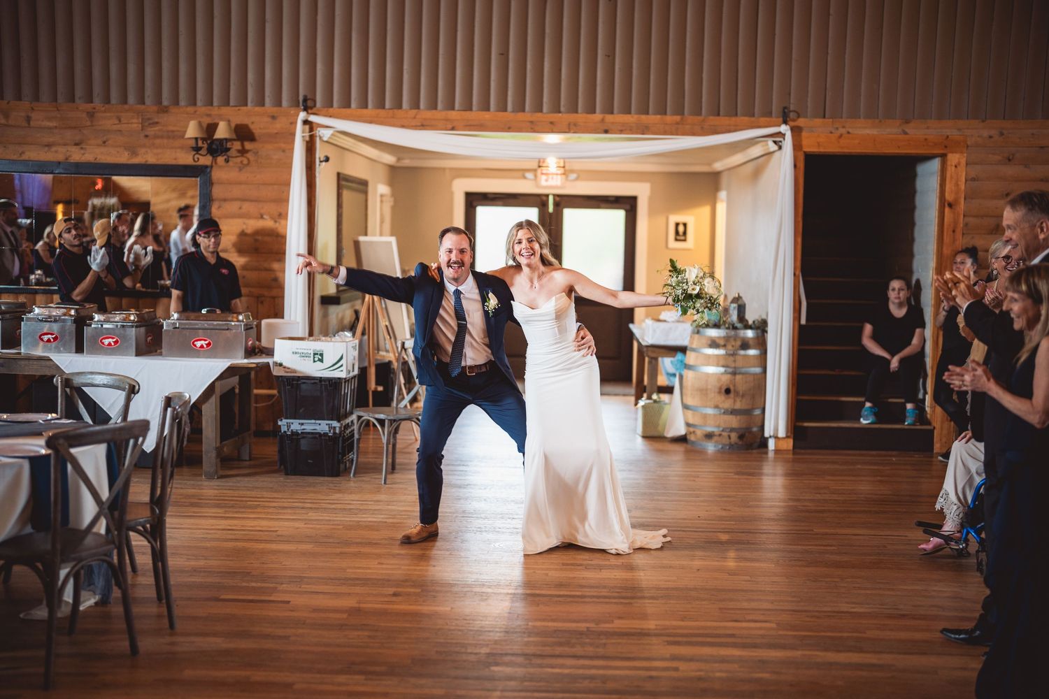 Large open event space with wooden walls and floors during a wedding celebration.