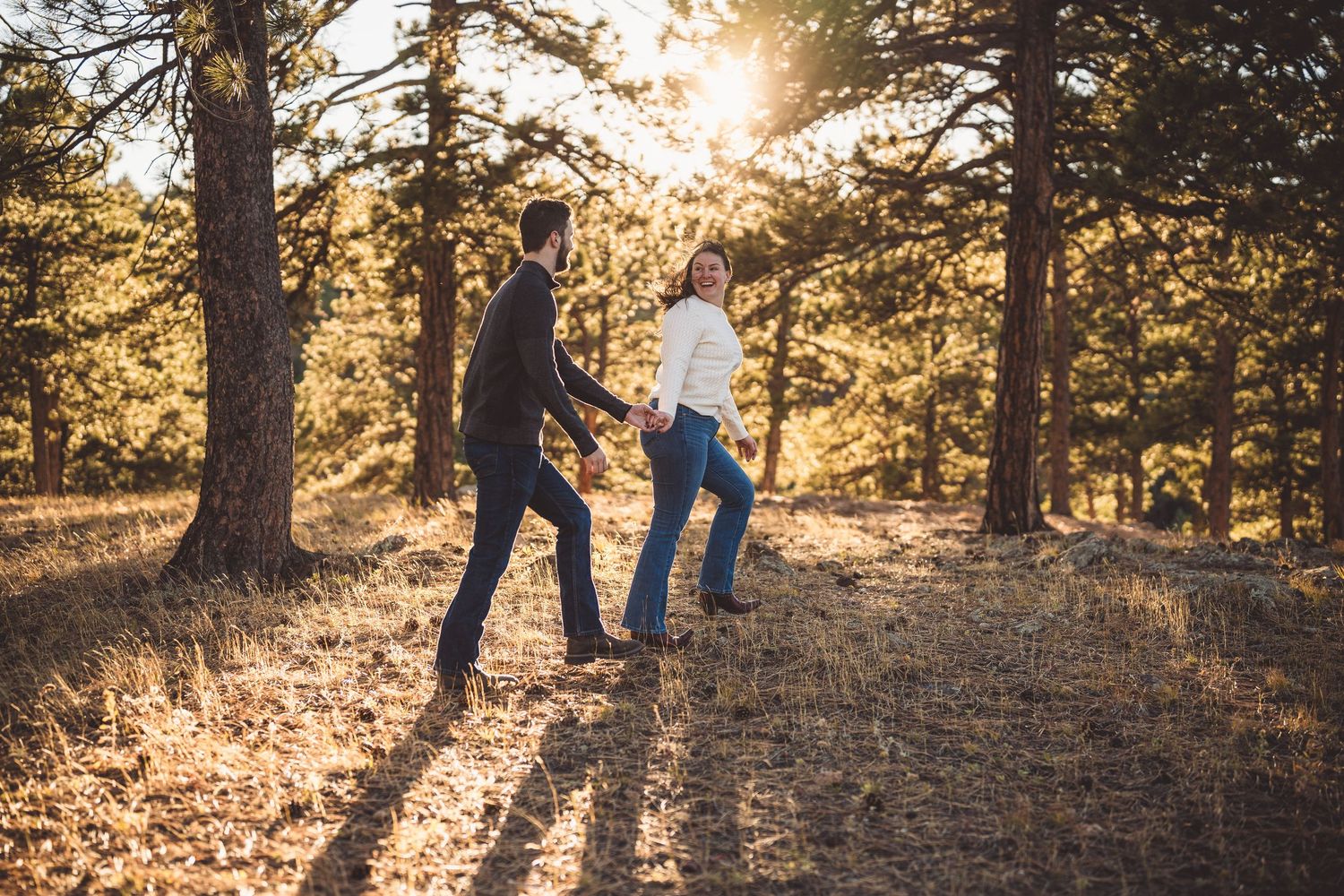 A couple dances together on a mountain trail during sunset with long shadows.