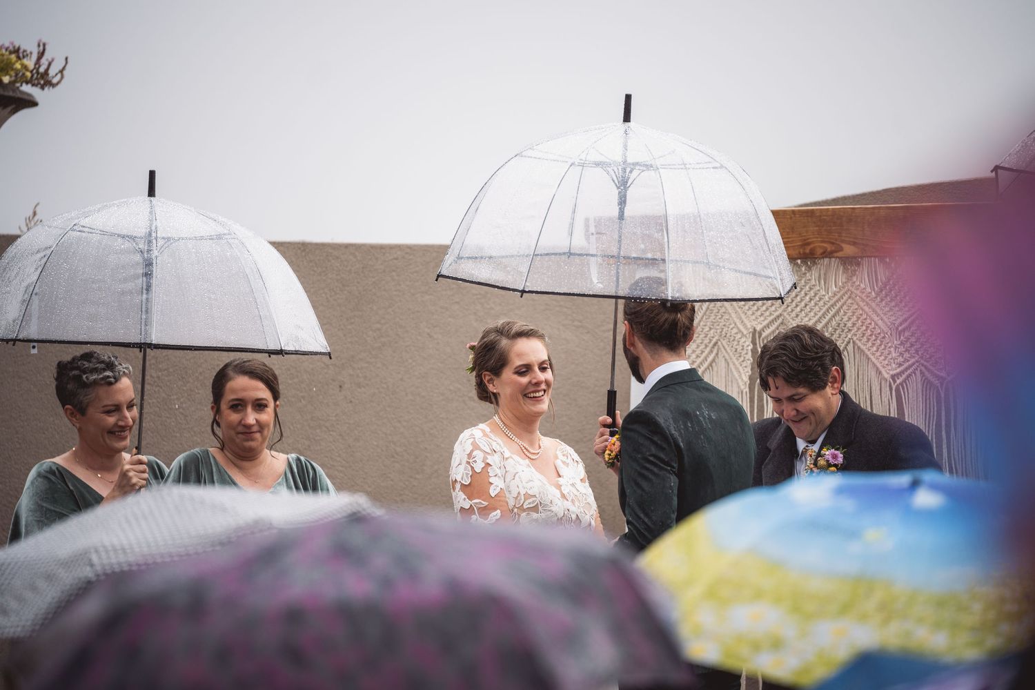 Wedding guests gathered under white umbrellas creating an elegant outdoor scene at dusk.