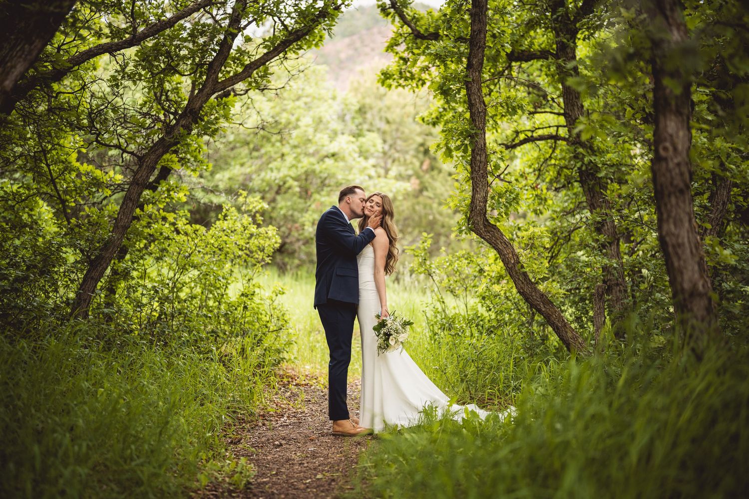 Wedding couple portraits in lush green garden pathway setting.