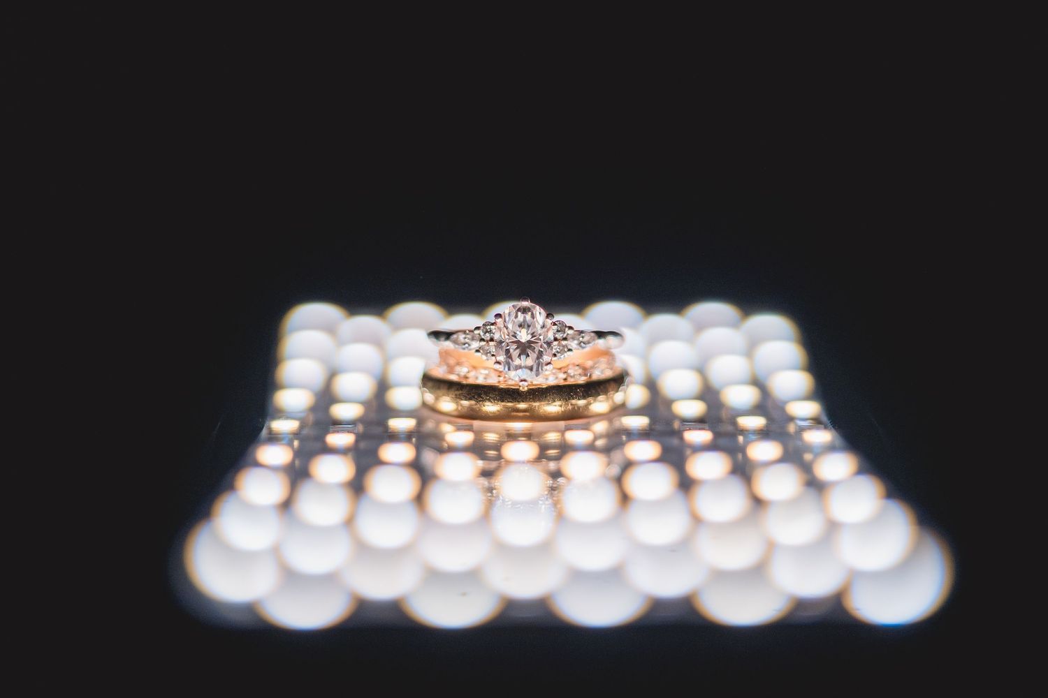 Close-up of an elegant diamond engagement ring set in rose gold, surrounded by tiny pearls.