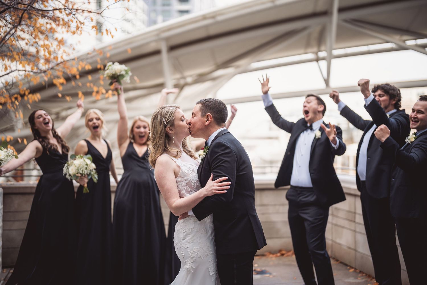 Wedding party gathered under an urban overpass with festive celebration.