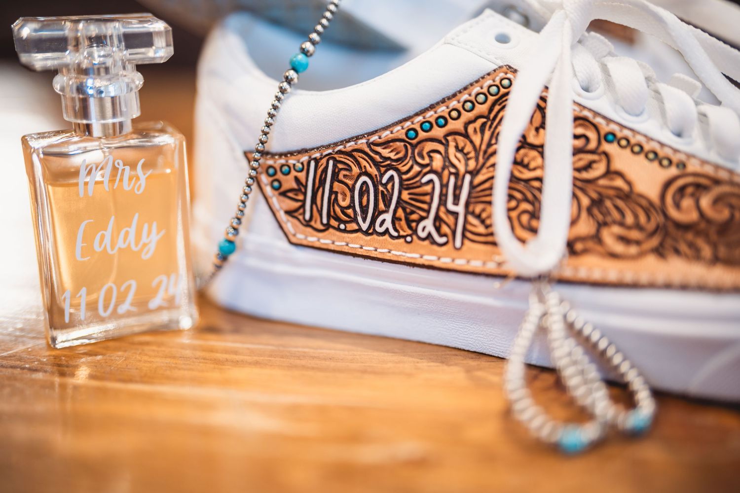 Wedding detail shot of personalized glasses and decorated shoes on wooden surface.
