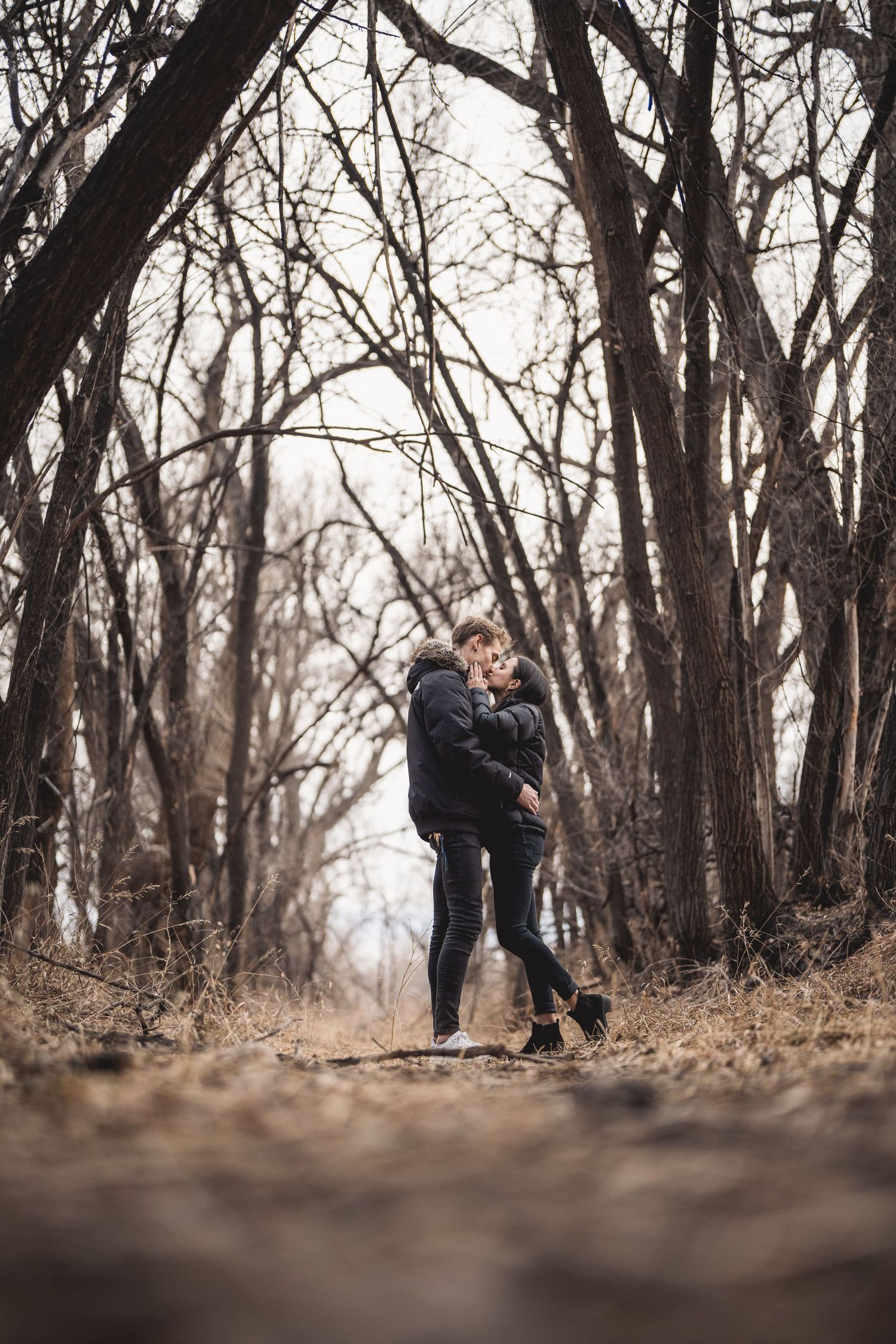 Two figures walking together on a leaf-covered forest trail.