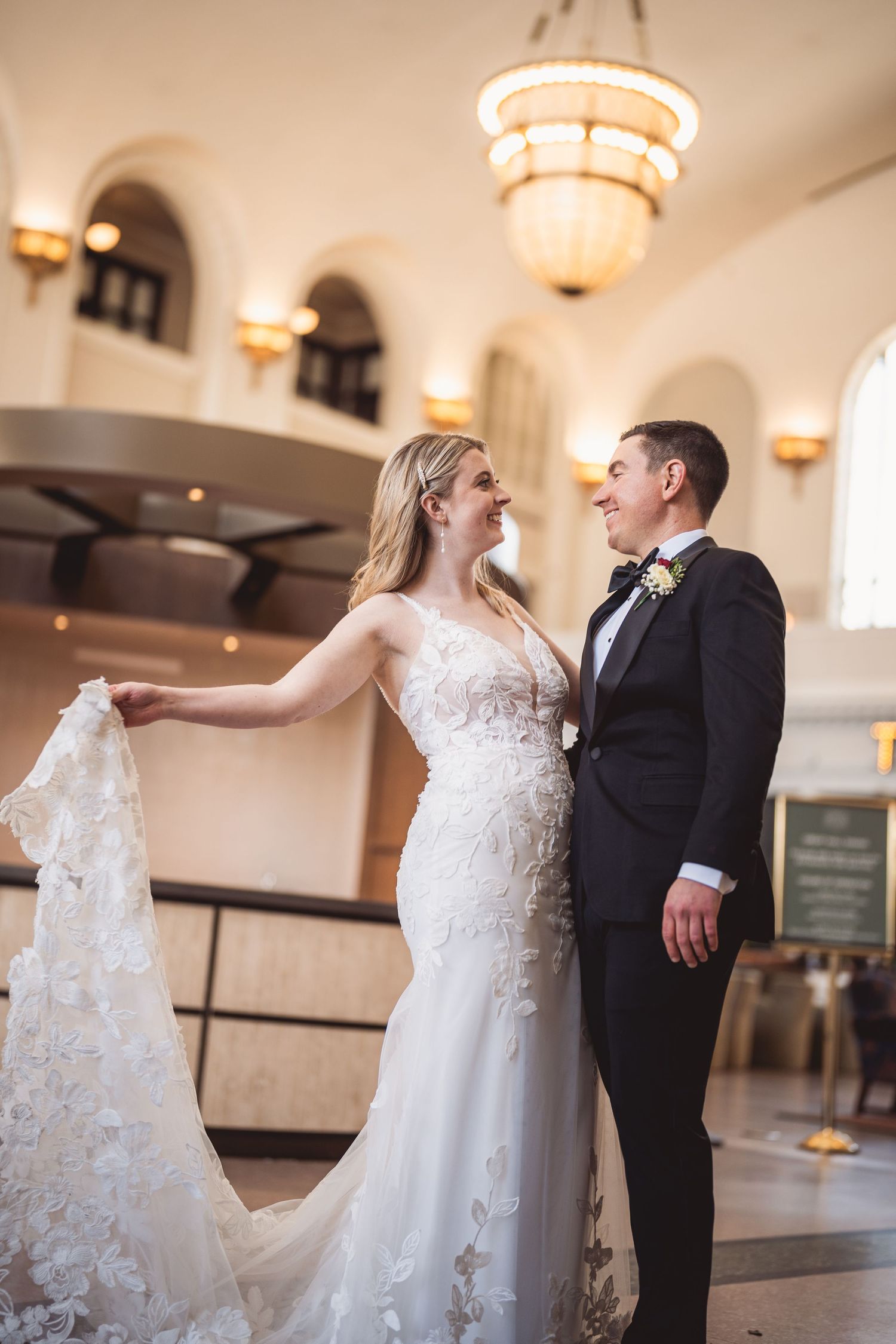 Wedding couple dancing and twirling in an elegant venue with ornate lighting.