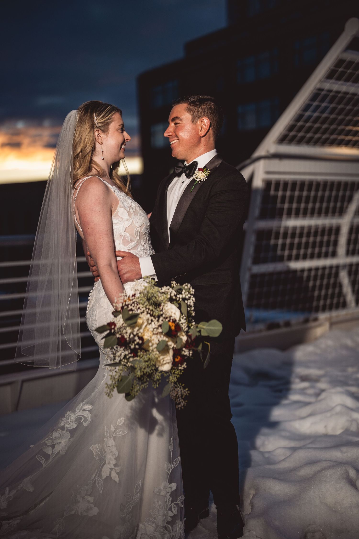 Newlyweds pose for romantic sunset photos against a modern architectural backdrop.