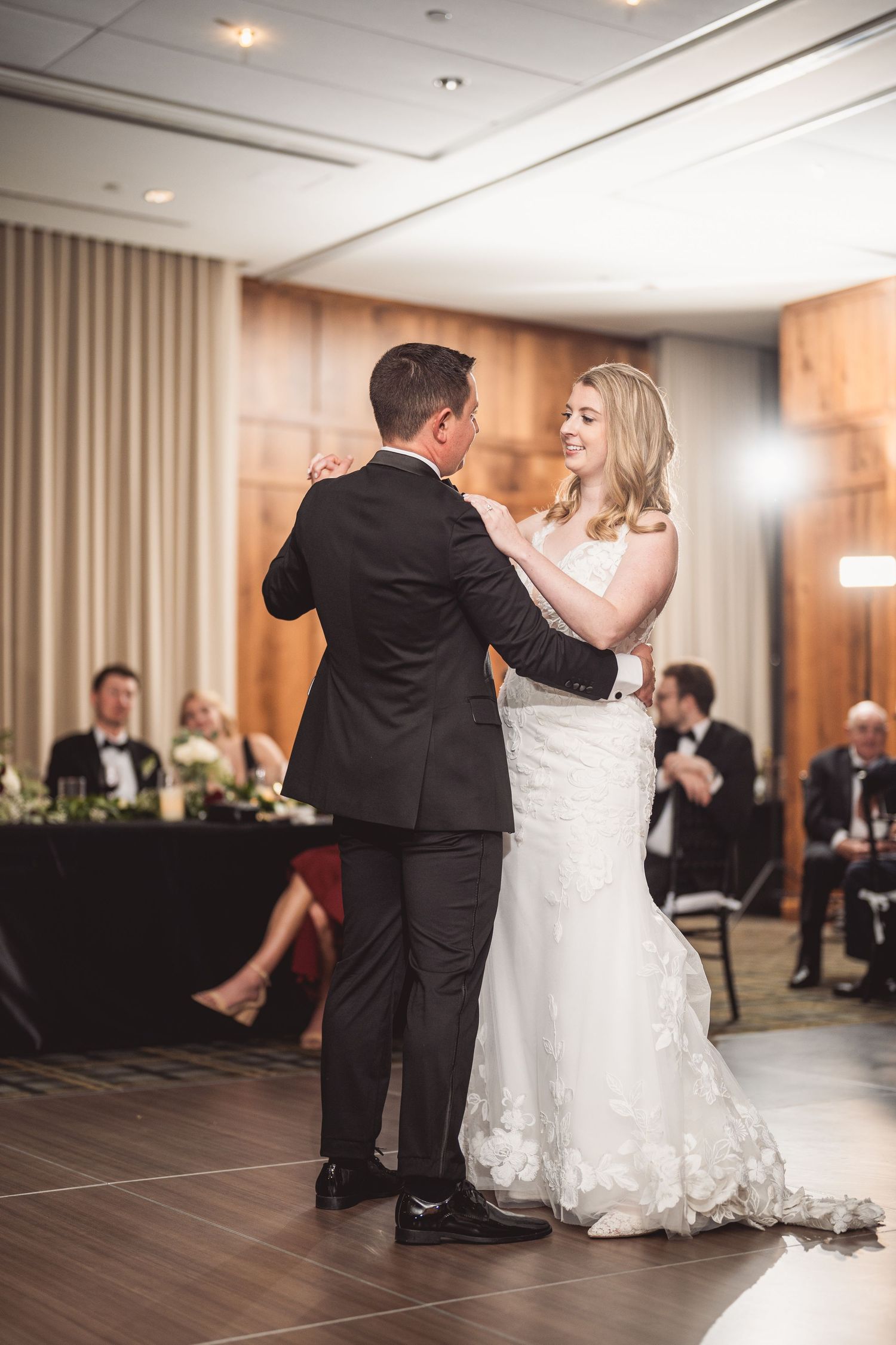 Elegant first dance performance in a modern ballroom with wood floors and neutral decor.