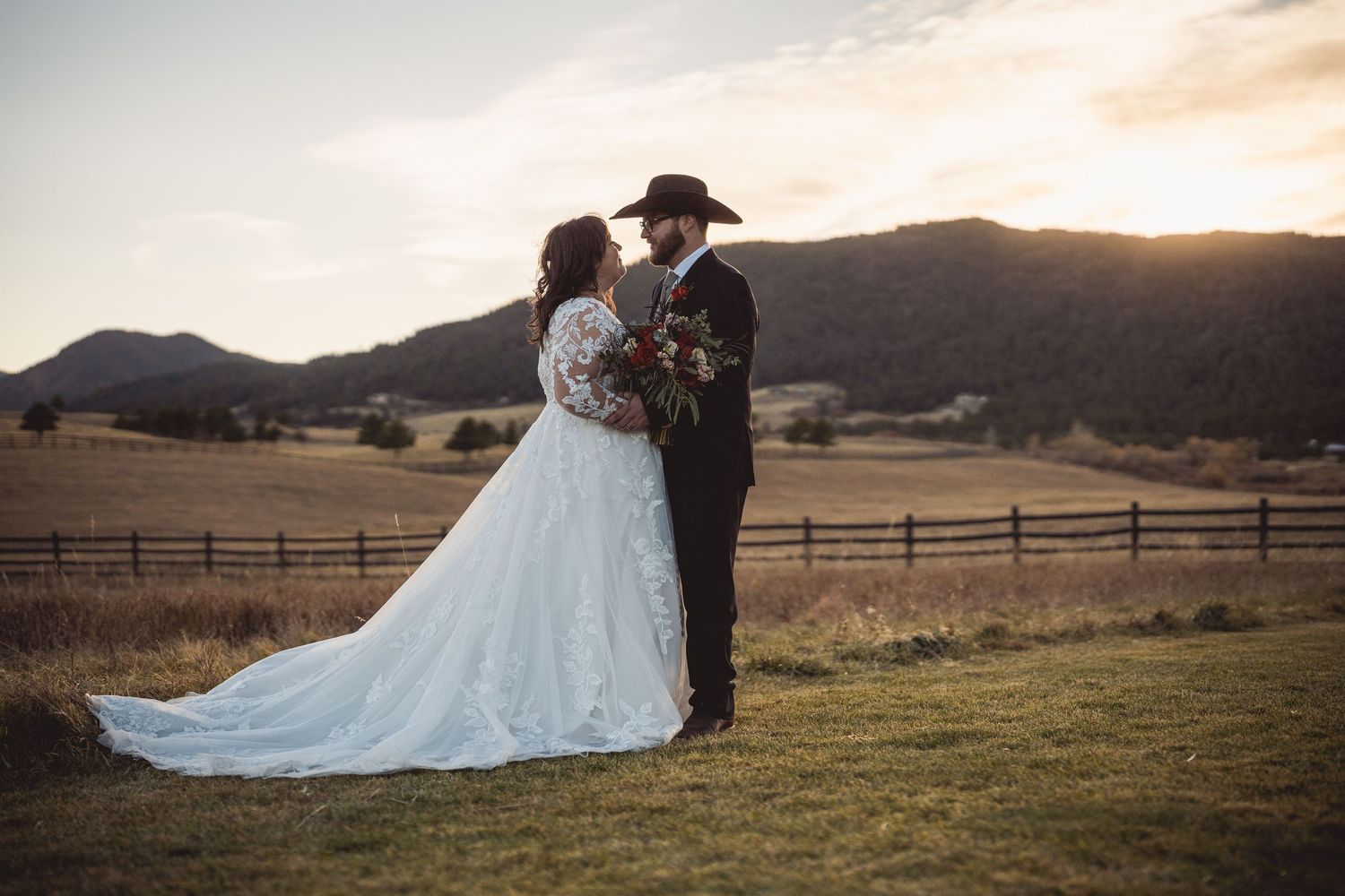 Scenic mountain wedding photos at sunset with couple embracing on grassy field.