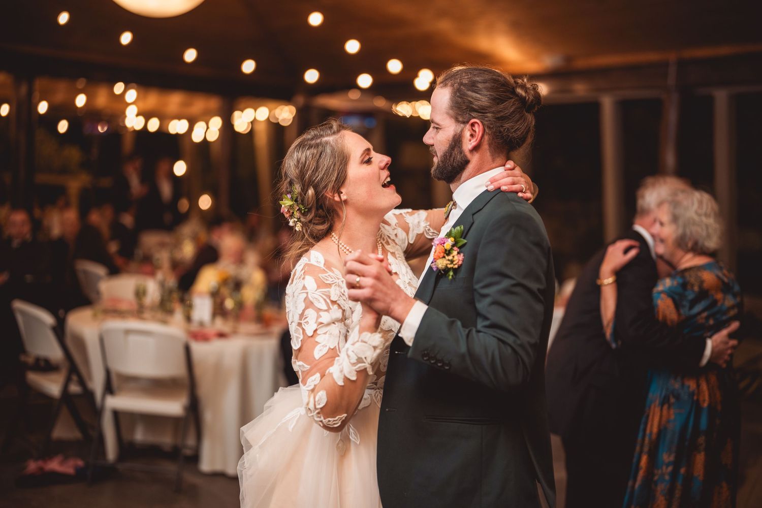 Couple performs their wedding dance under ambient lighting in a rustic venue setting.