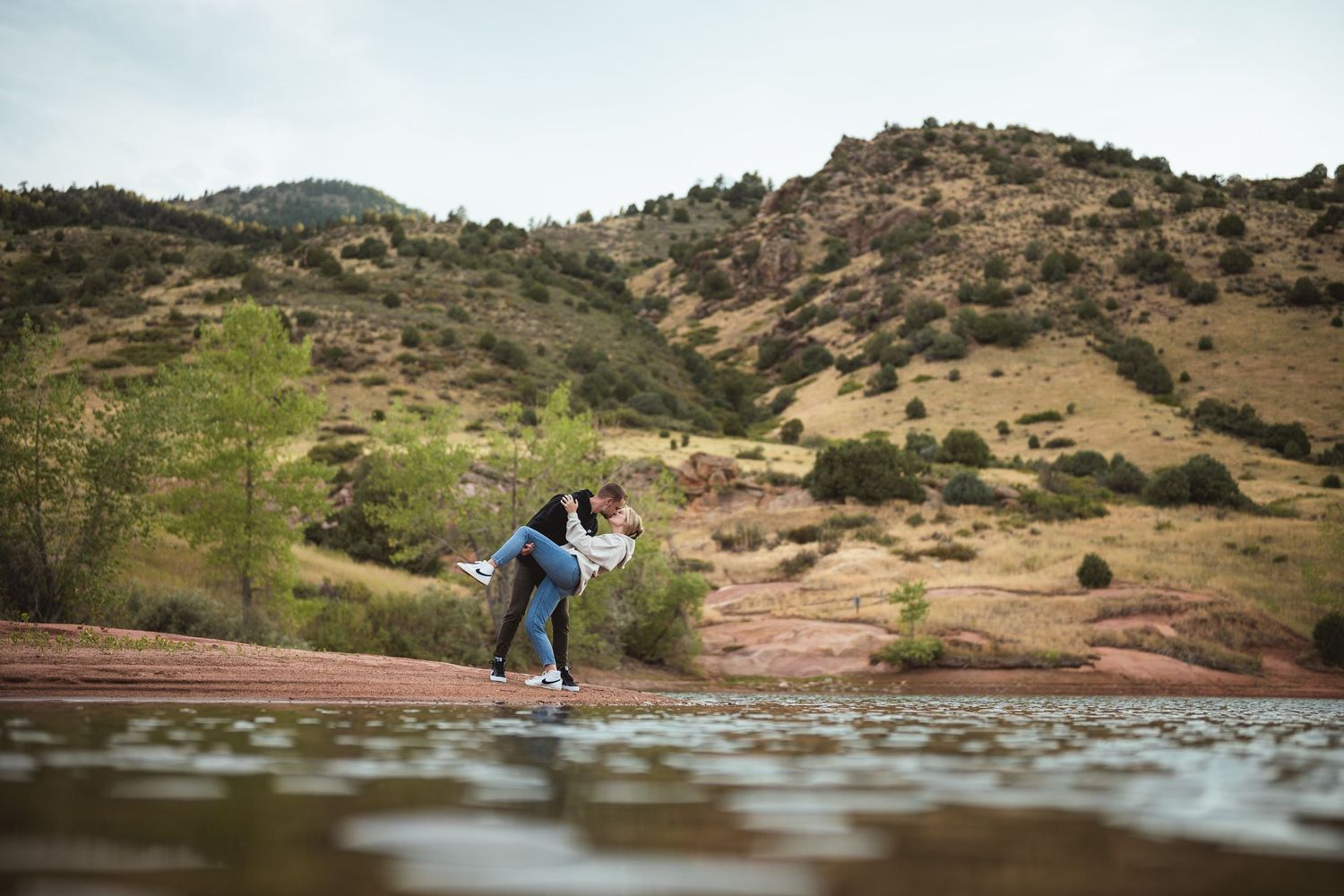 Couple's portrait session at red rock reservoir with mountain backdrop.