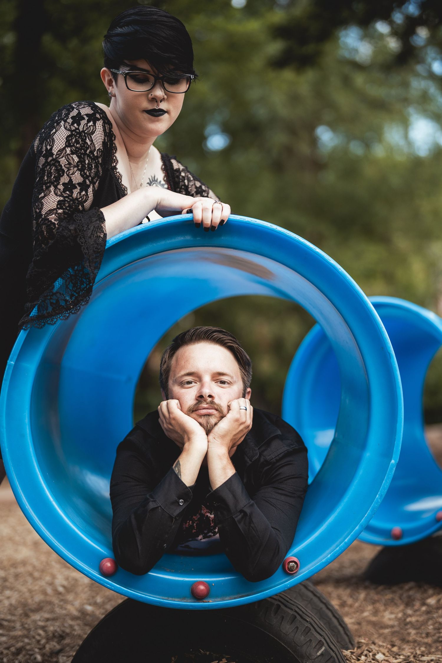 Creative outdoor portrait of someone lying in a blue curved seat against a natural background.