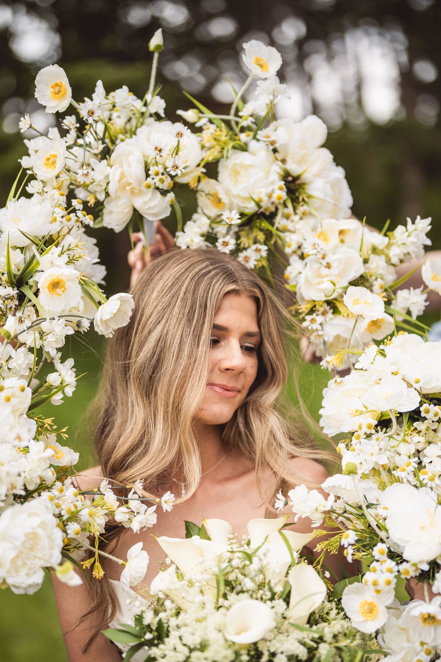 Delicate white floral crown and spring blossoms create romantic portrait.