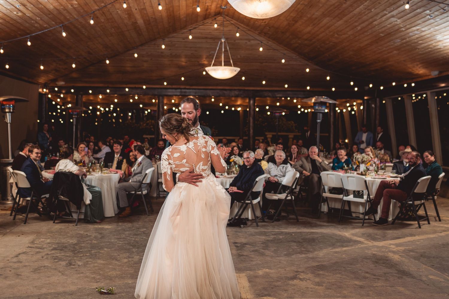 Rustic wedding reception venue with wooden ceiling and twinkling string lights.