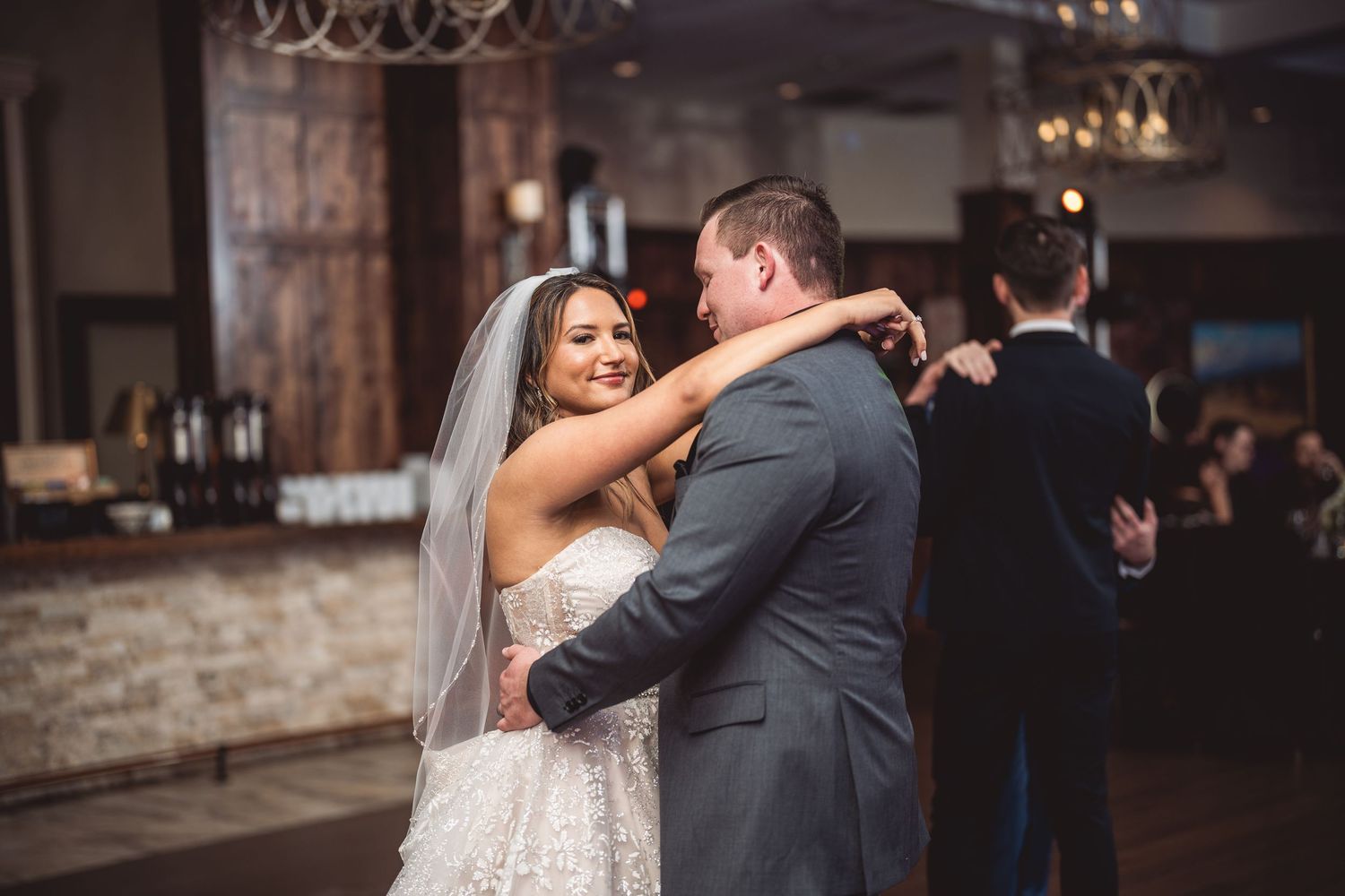 Couple shares romantic dance moments during wedding reception in rustic-themed venue.
