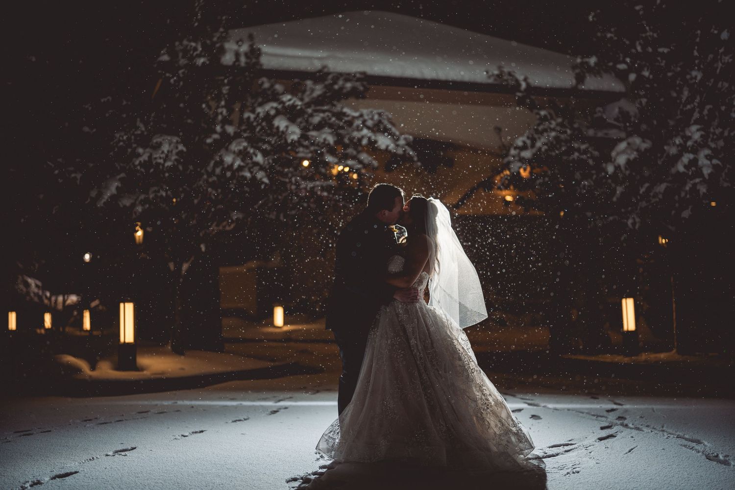 An elegant princess-style wedding dress photographed in a snowy evening setting.