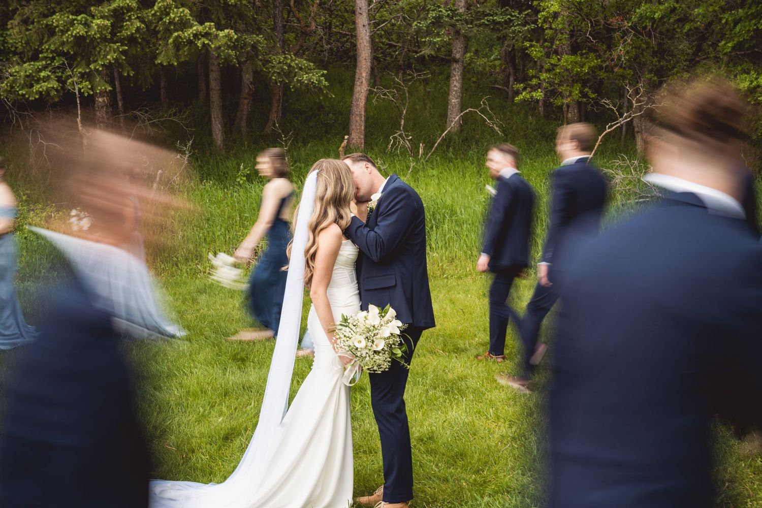 Wedding celebration in wooded area with party members in coordinated attire.