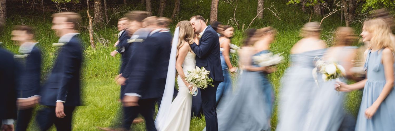 Motion-blurred shot of wedding party celebrating outdoors in blue attire.